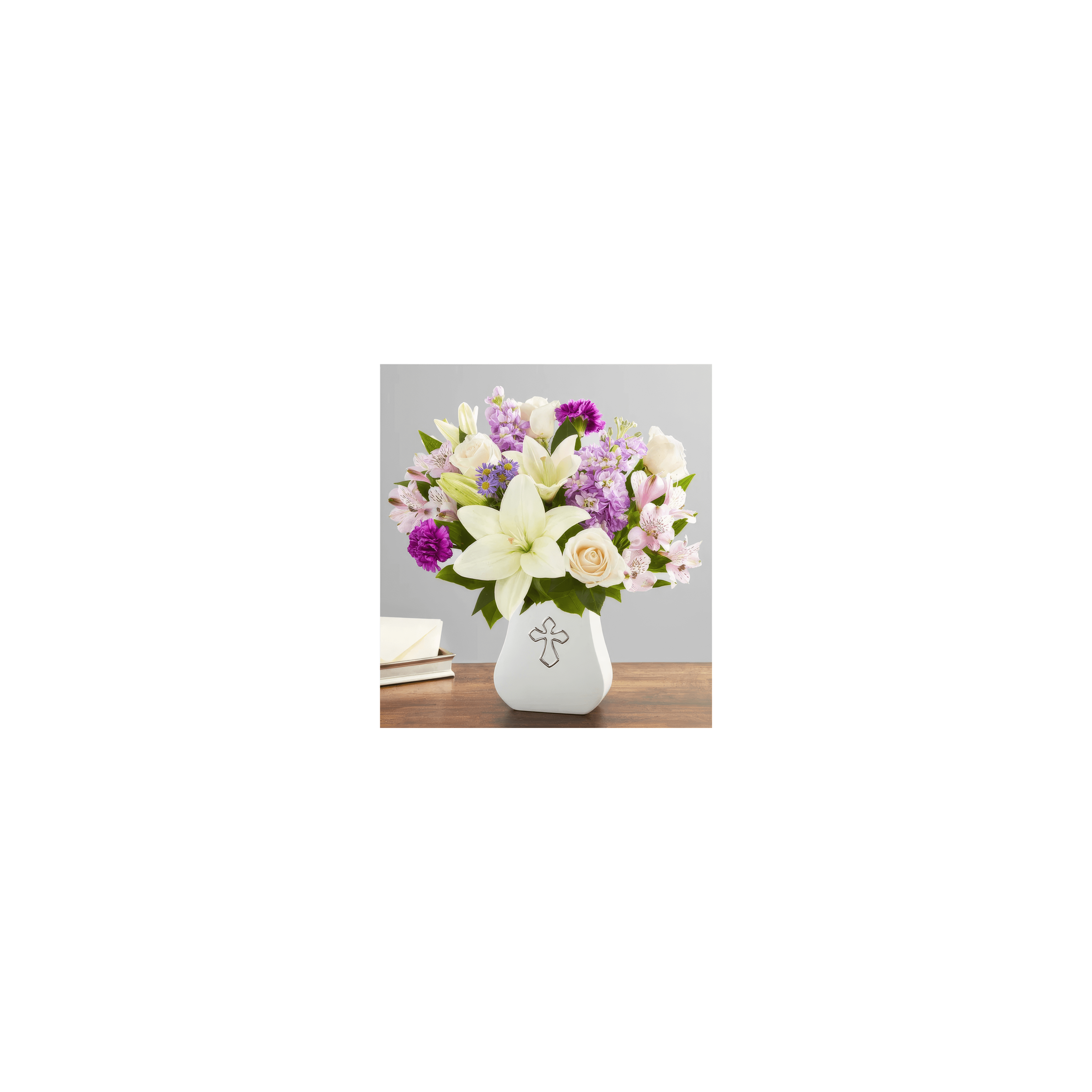A vibrant mix of flowers in a cross-decorated vase sits on a wooden table, radiating beauty.
