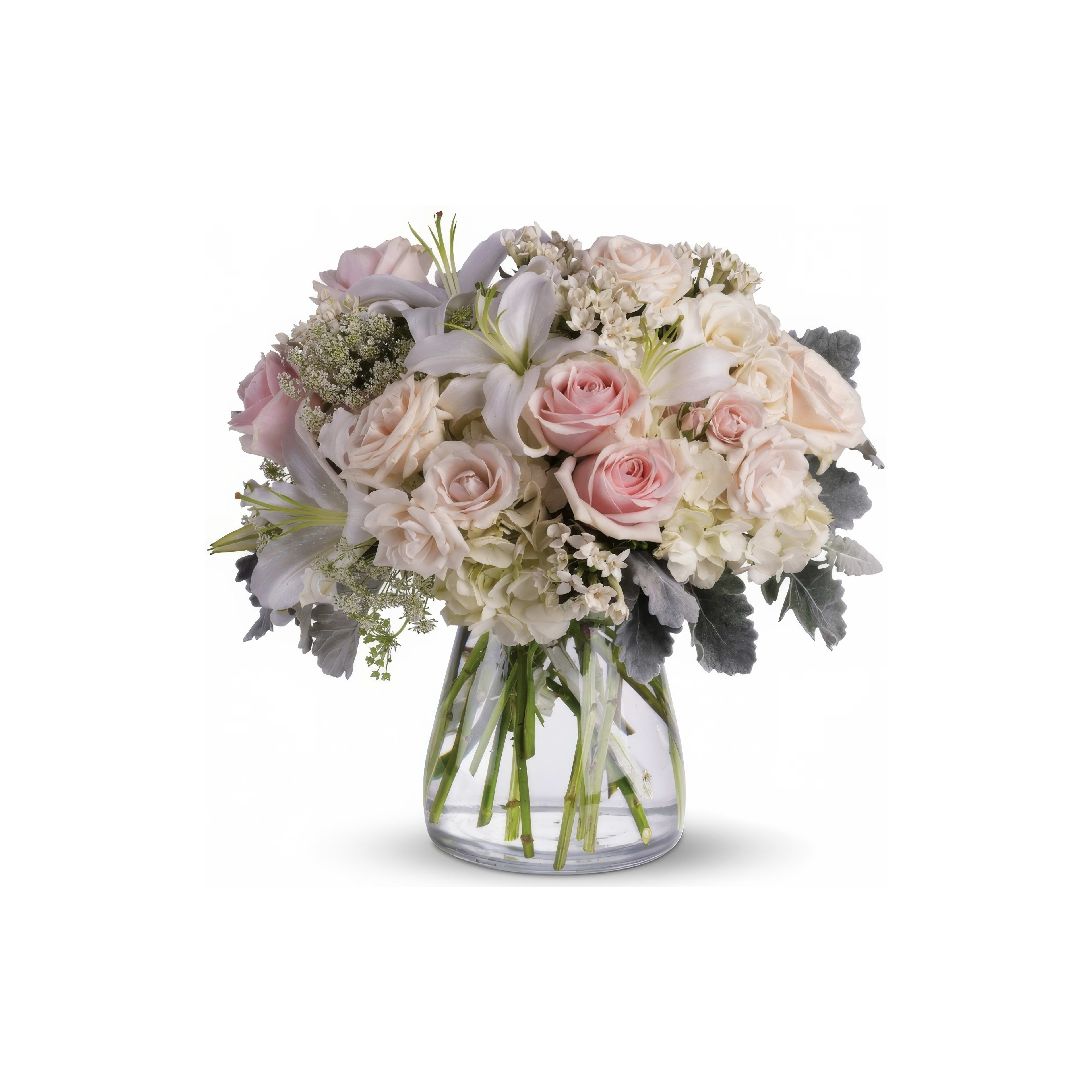 A stunning floral arrangement with soft pink roses, white lilies, and lush greenery in a clear vase.