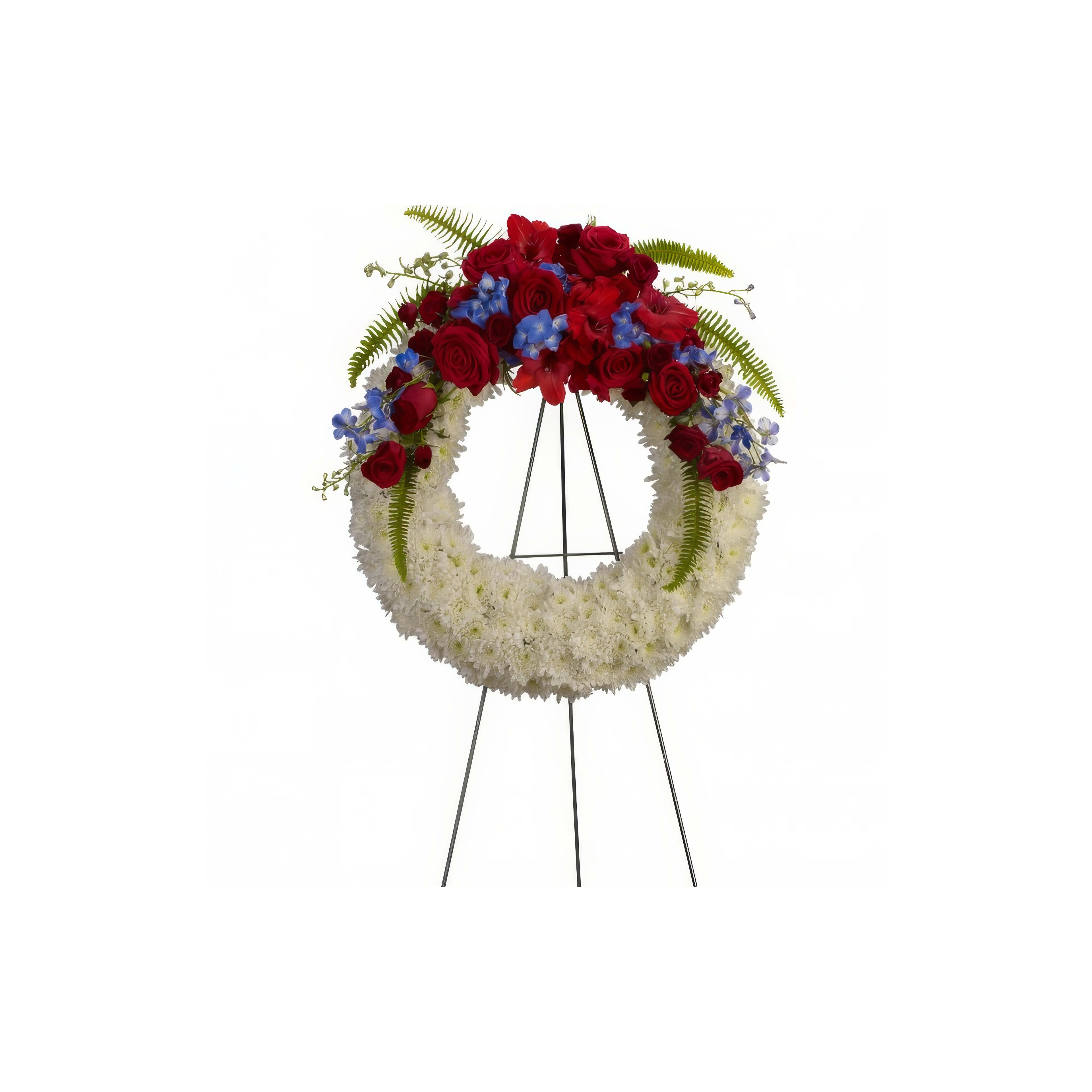 A beautifully arranged floral wreath features red roses and blue flowers with lush ferns.