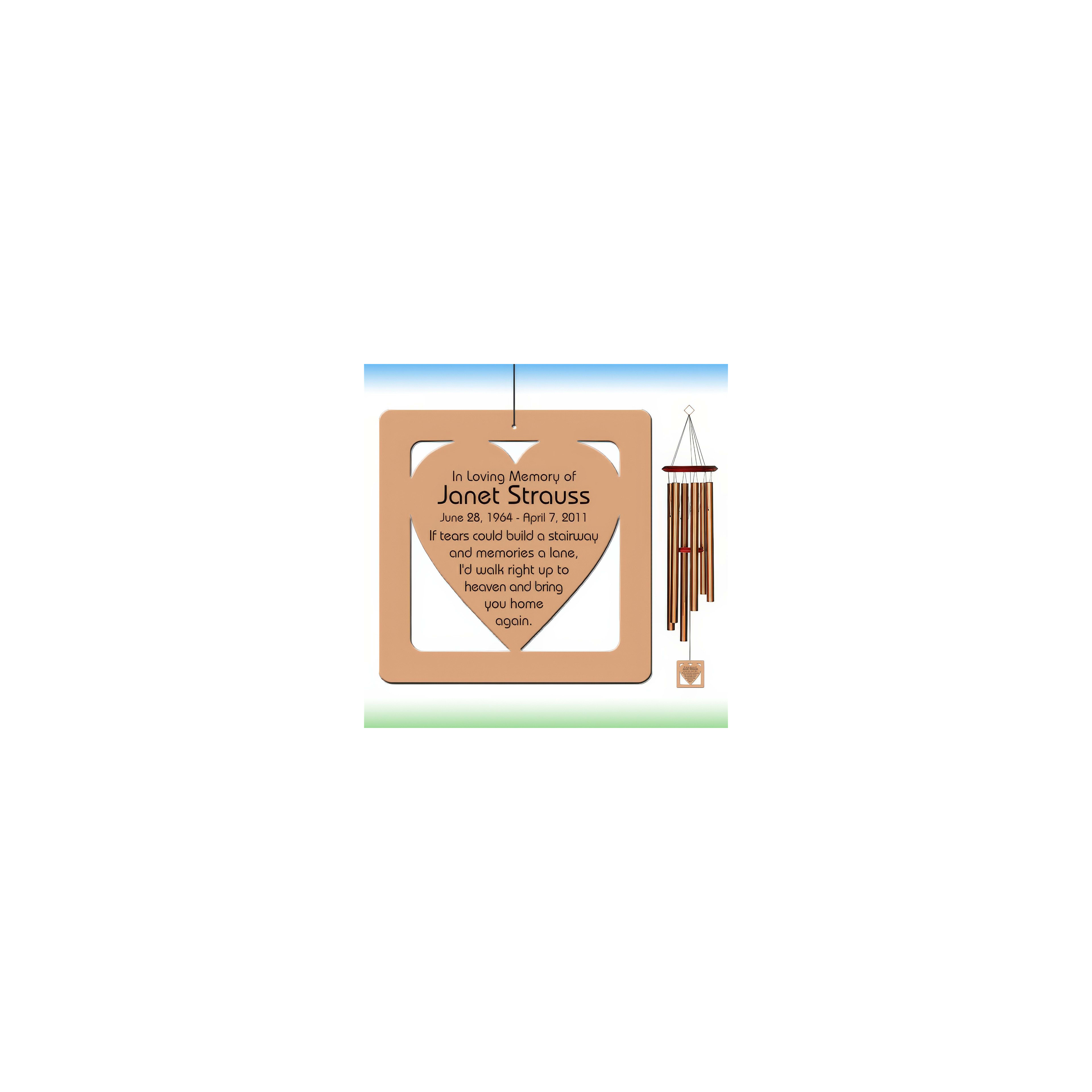 A wooden memorial plaque sits beside wind chimes, honoring Janet Strauss in a peaceful environment.