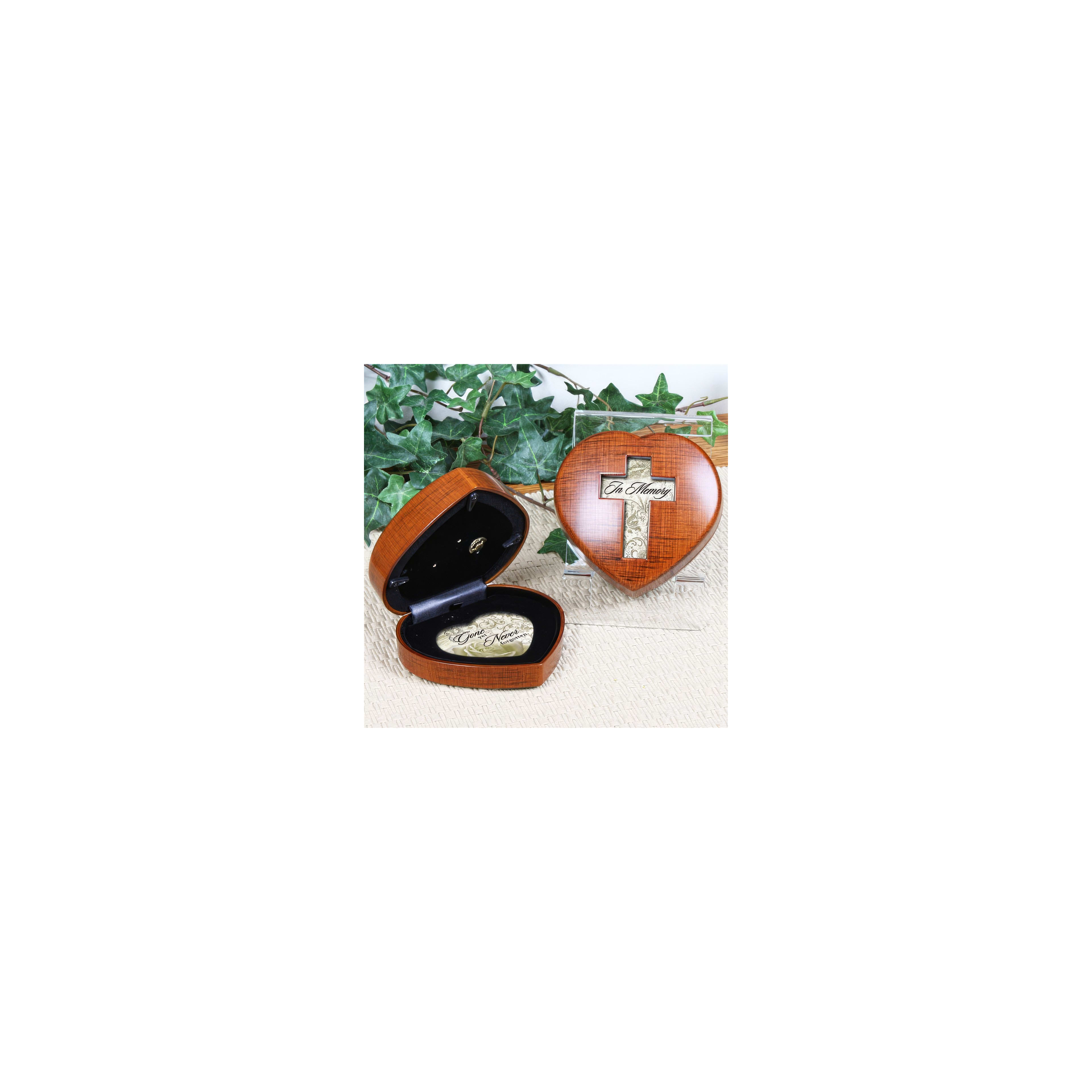 An open heart-shaped wooden box with a cross shows a keepsake on a soft surface.