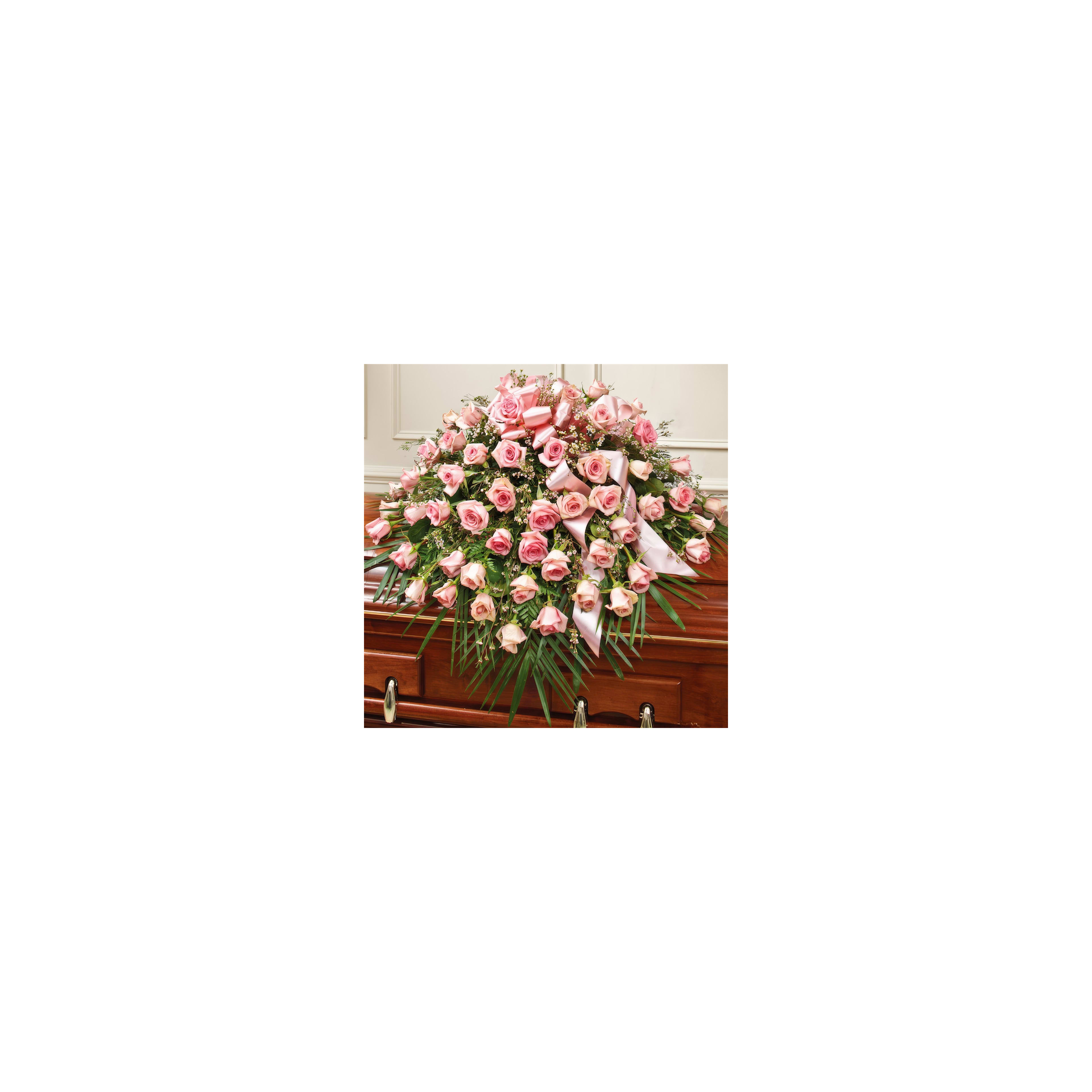 A stunning arrangement of pink roses decorates a wooden casket in a peaceful room.