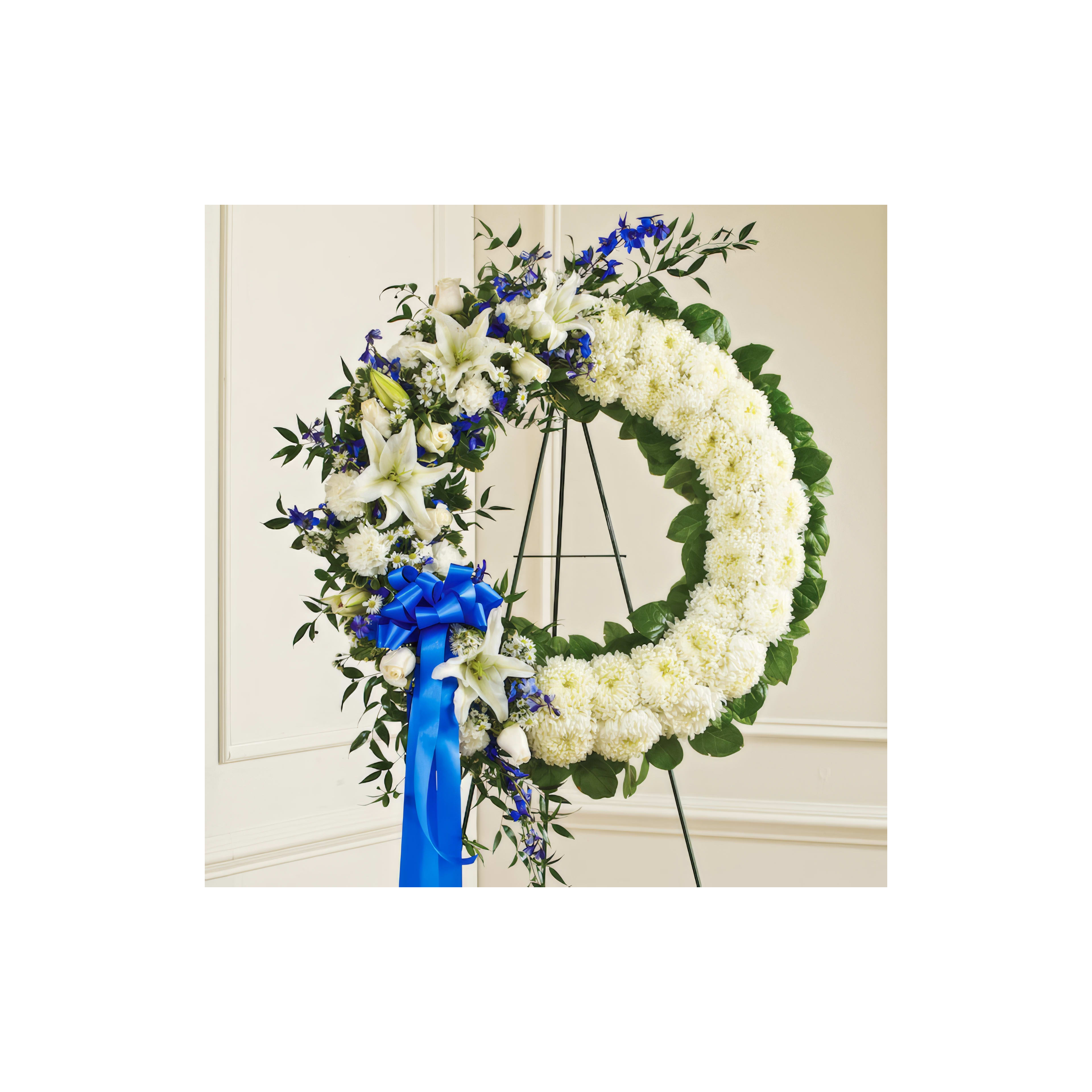 Elegant floral arrangement featuring white lilies and blue flowers for honoring a loved one.