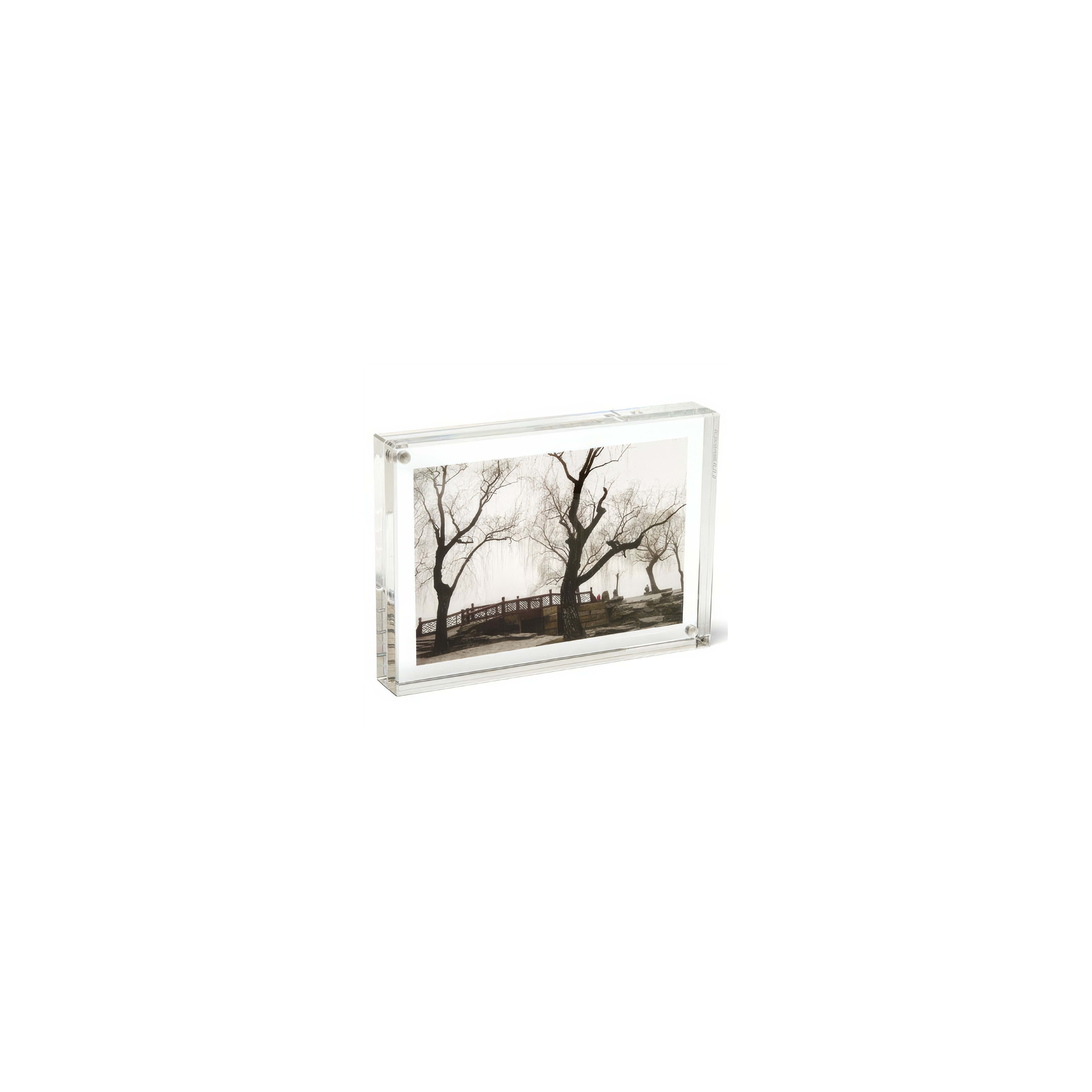 Artwork displays bare trees by a tranquil bridge during winter, creating a peaceful scene.
