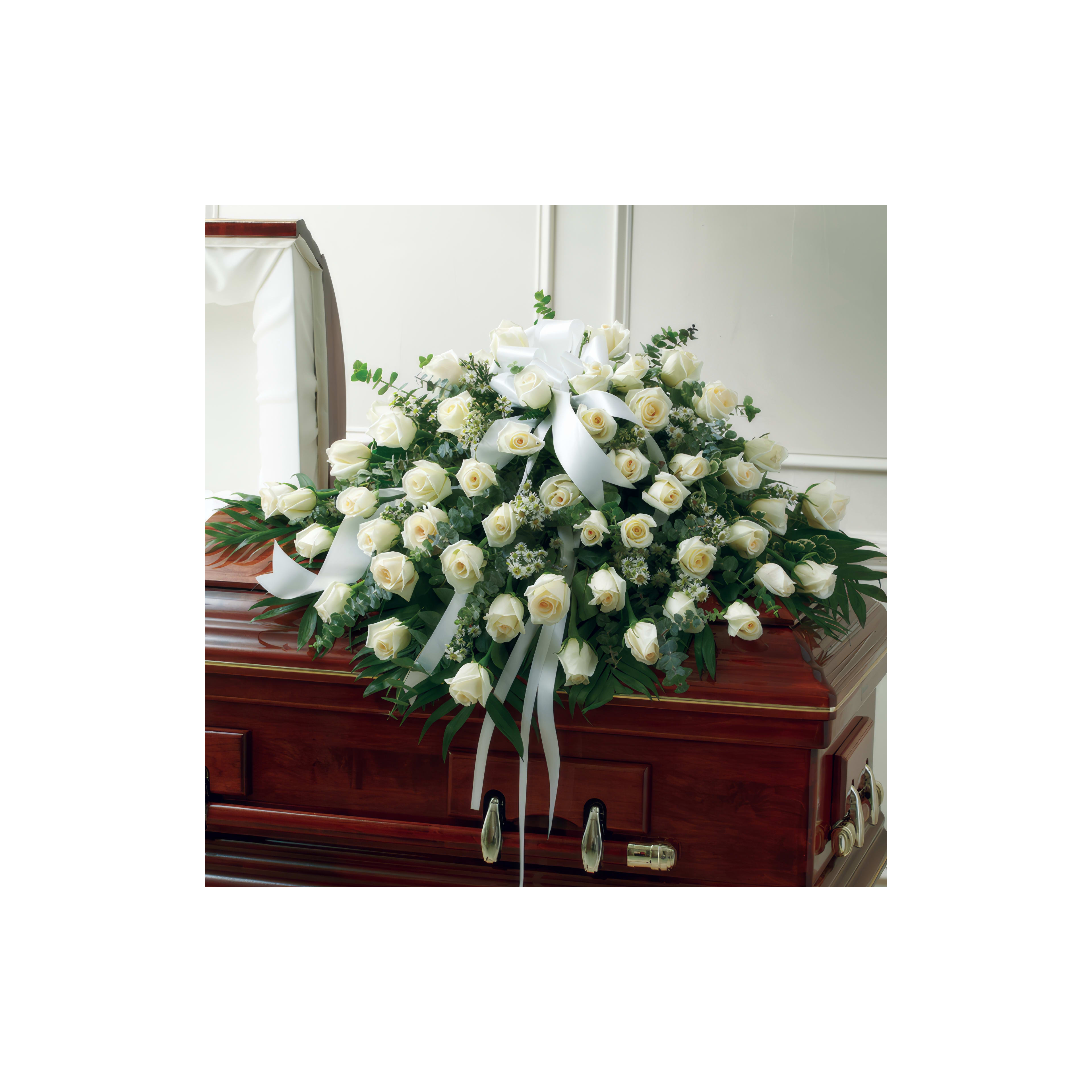 White roses and greenery decorate a wooden casket at the memorial service.