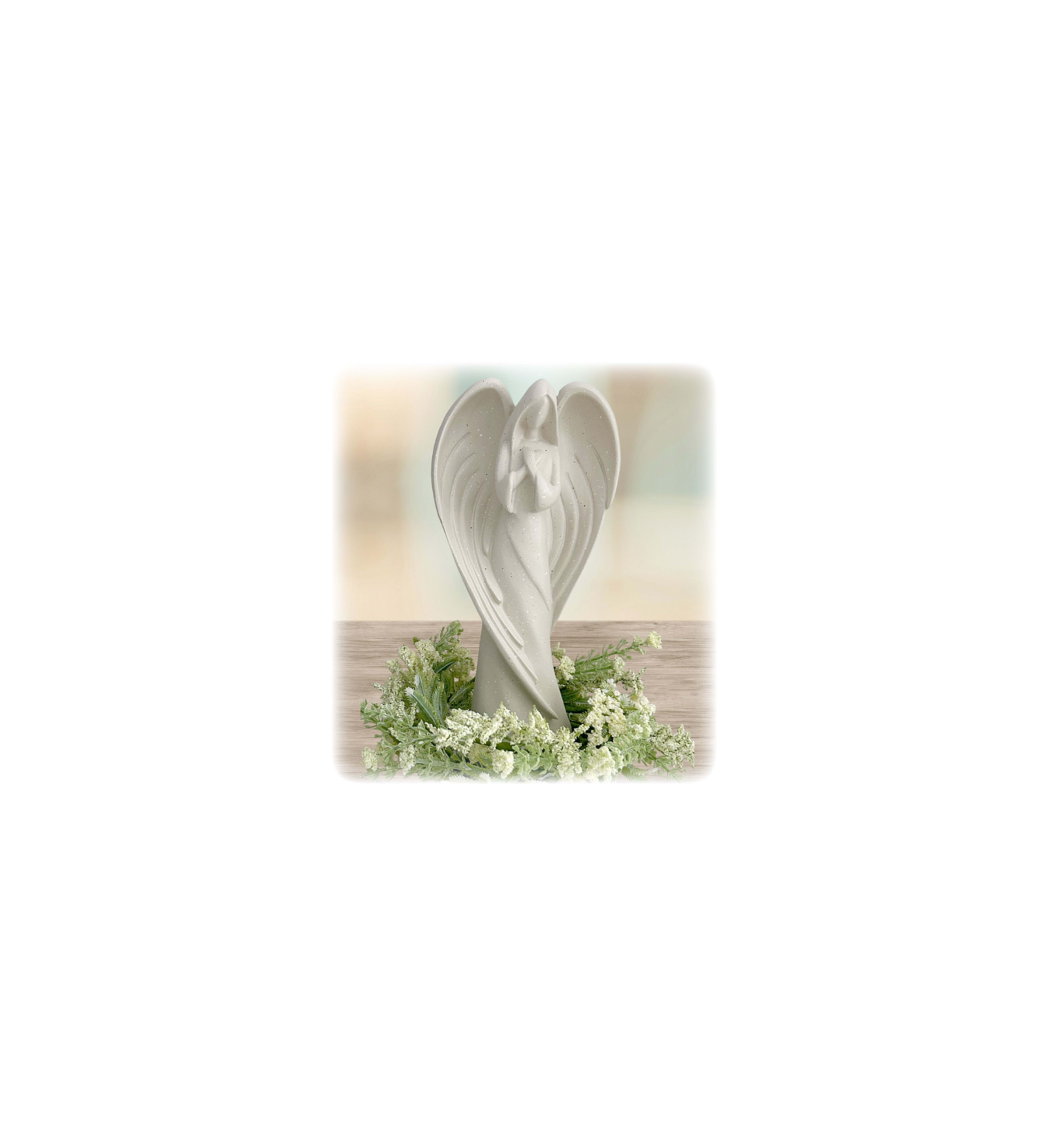 A white angel statue with flowers around it
