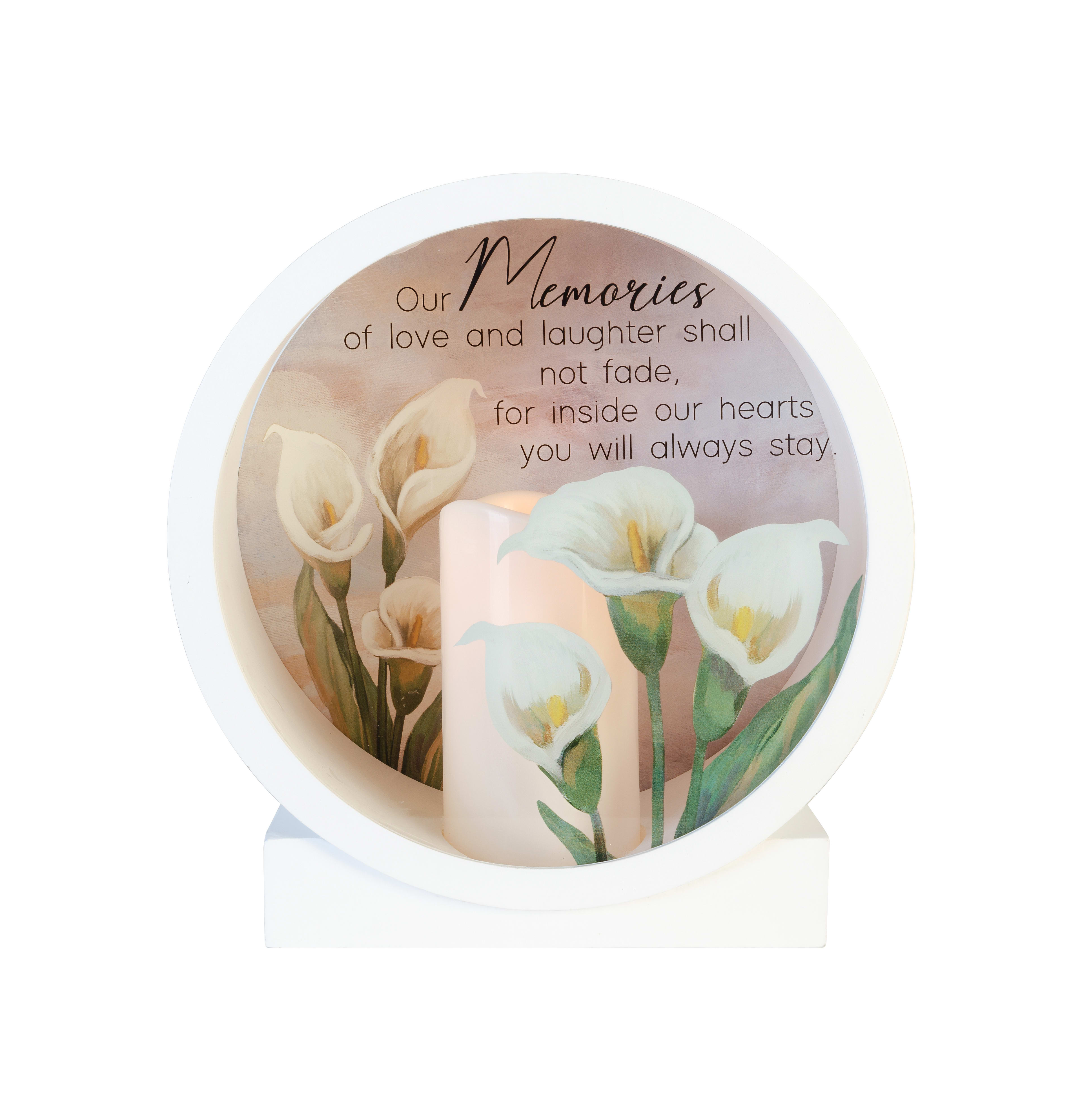 A candle holder showcases beautiful lilies and a touching sentiment about enduring memories.