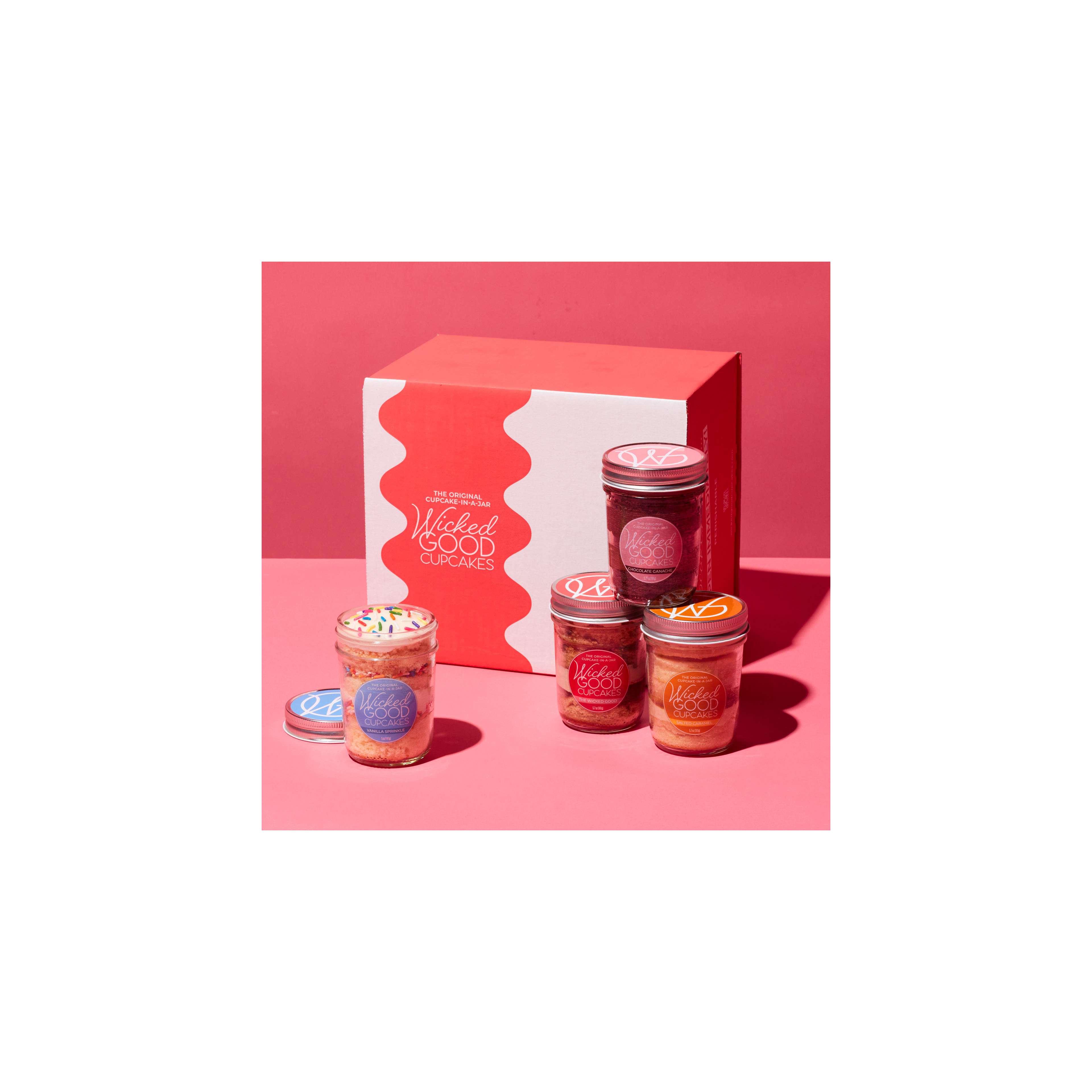Dessert jars filled with cupcakes showcase vibrant designs against a bright pink background.