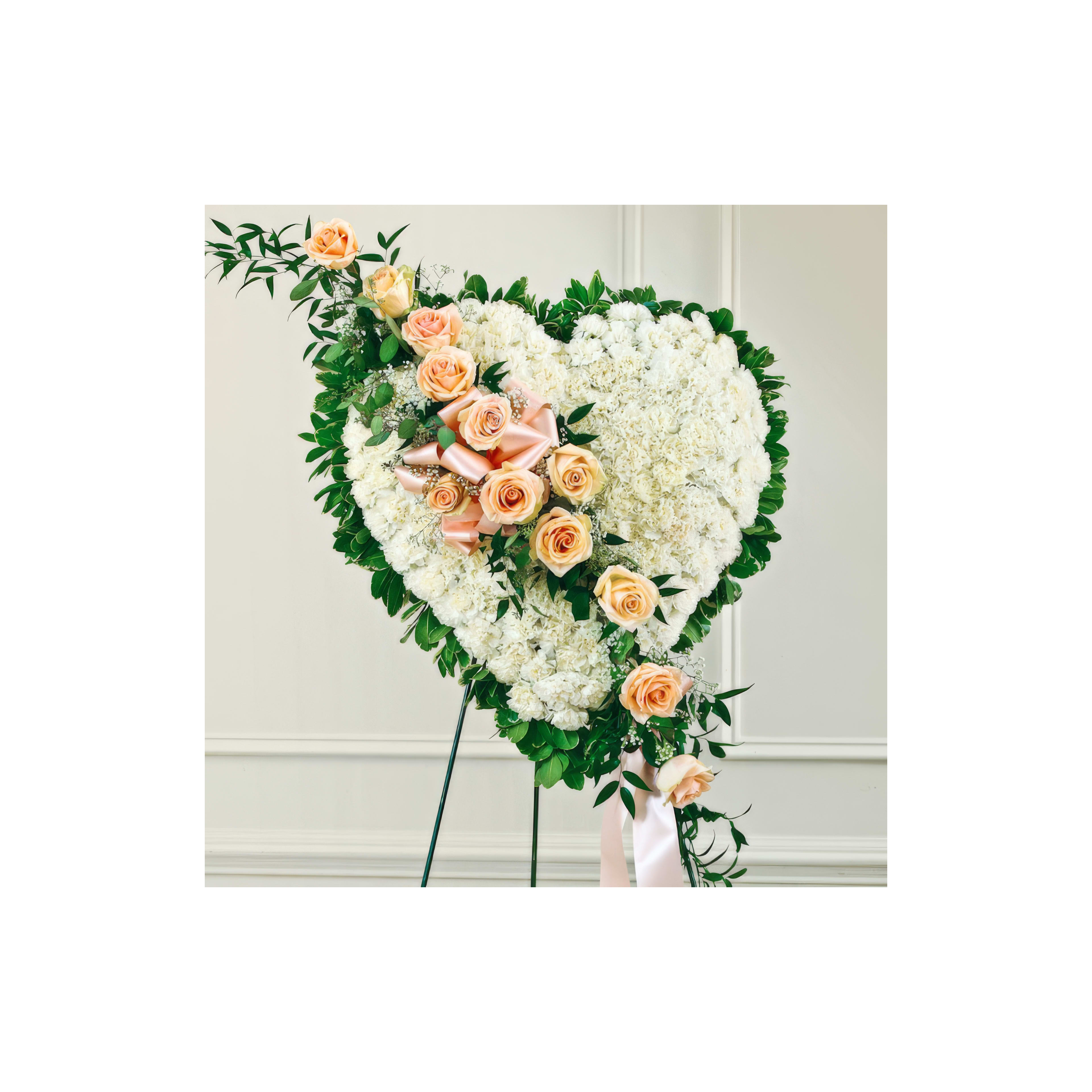 A heart-shaped floral arrangement of peach roses and greenery, ideal for a heartfelt occasion.