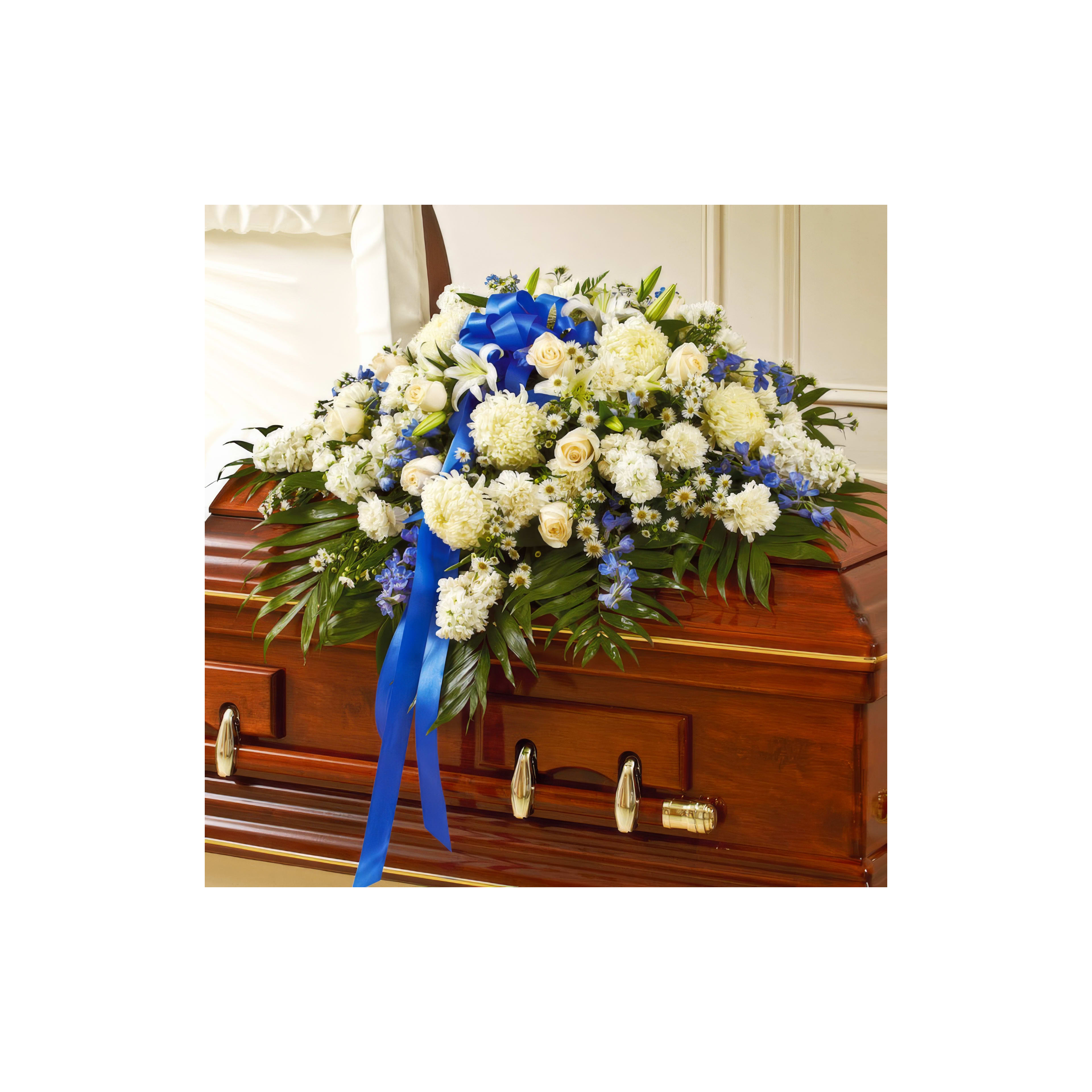 A beautiful mix of white and blue flowers decorates a polished wooden casket in a quiet room.