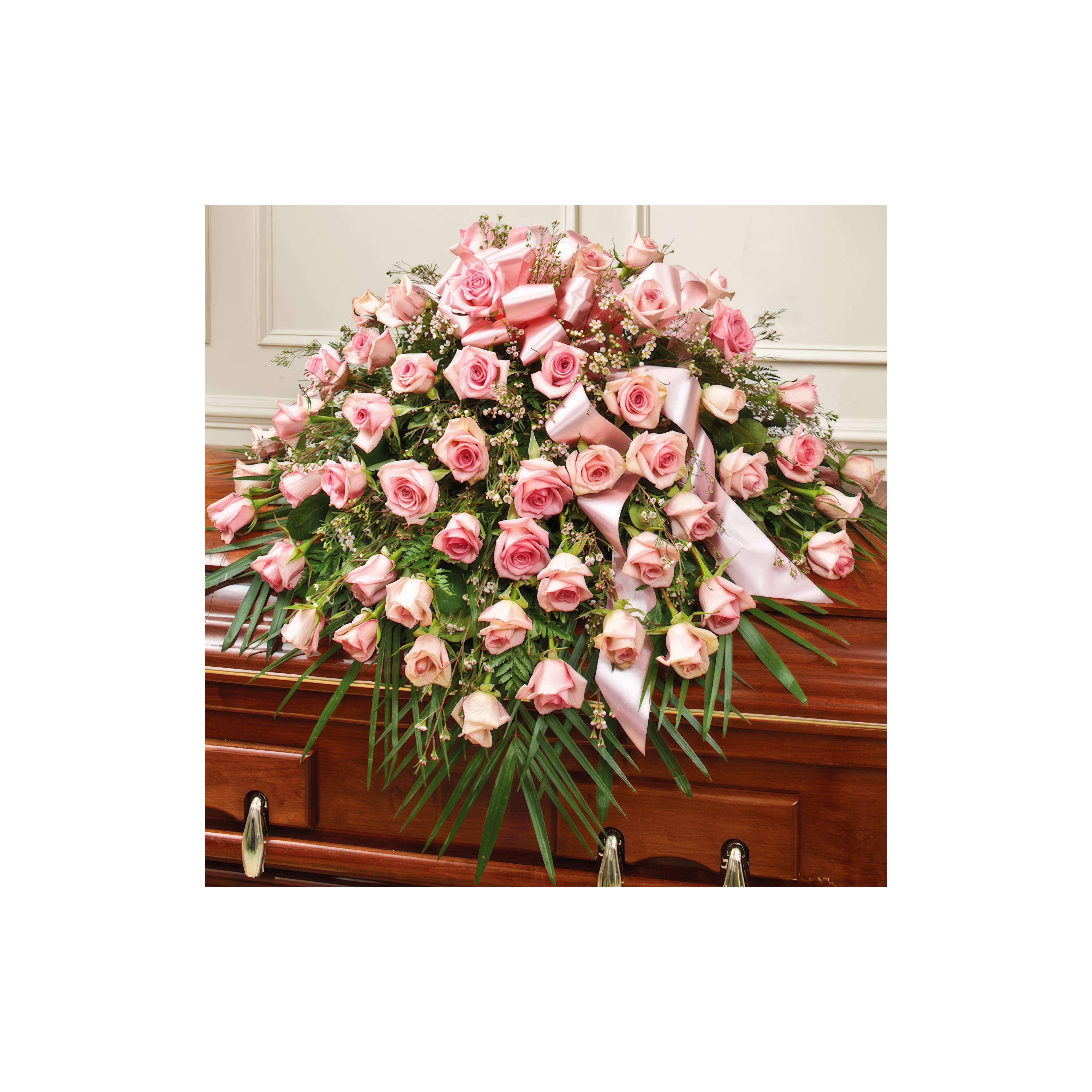 A beautiful array of pink roses with ribbons is placed on a wooden casket at the service.