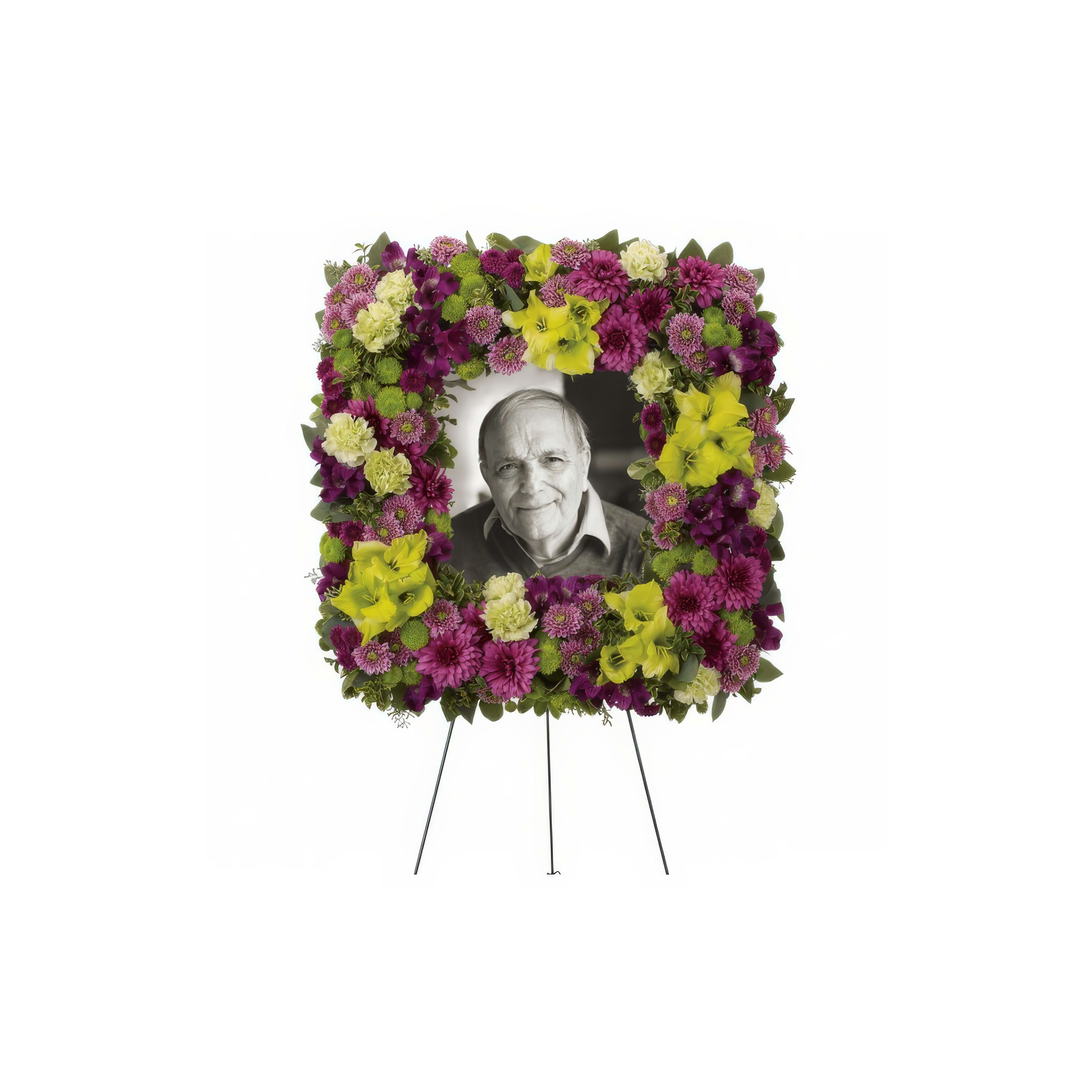 A beautiful arrangement of purple and yellow flowers framing a portrait in a heartfelt memorial.