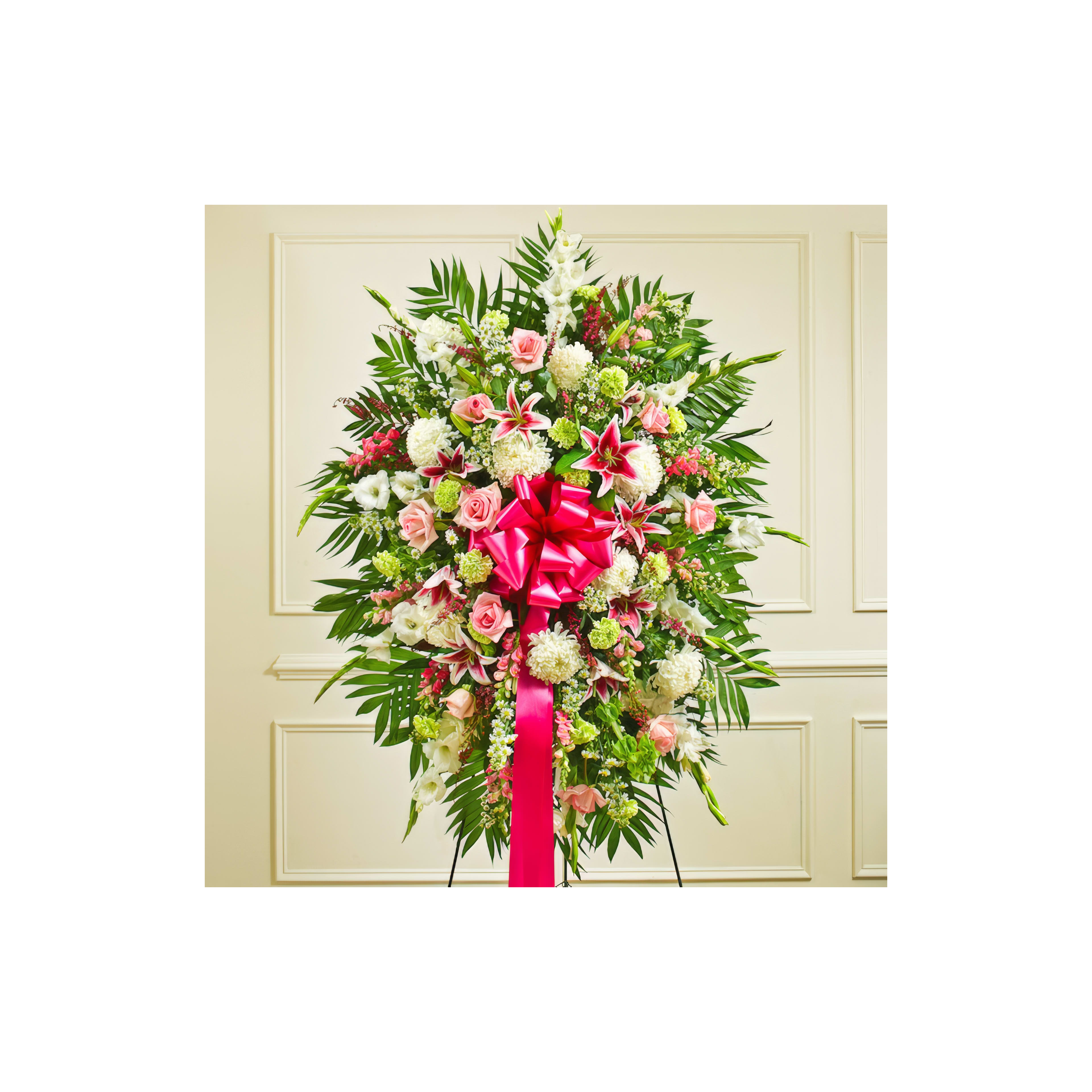 A vibrant arrangement of pink roses, white lilies, and greenery with a pink bow indoors.