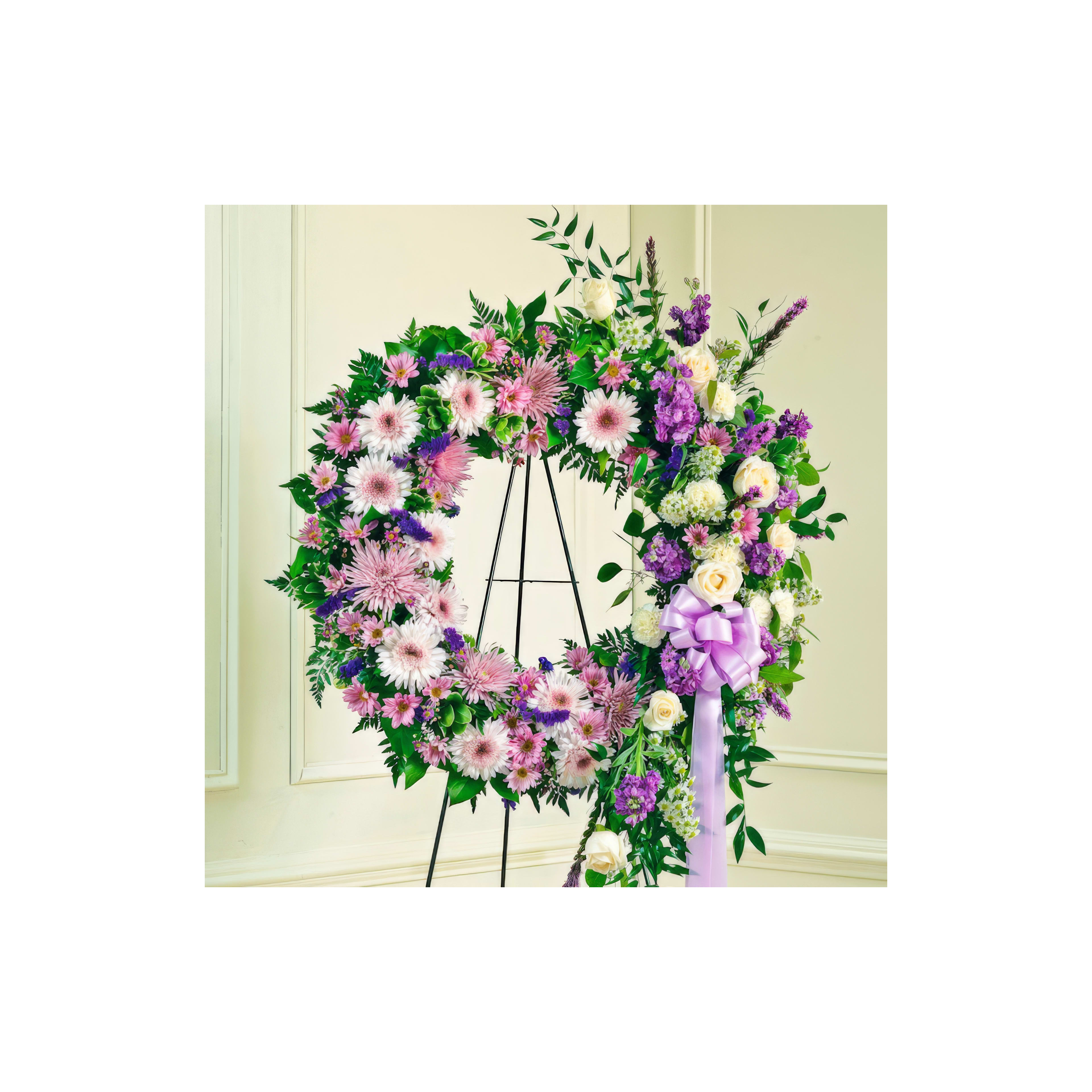 A colorful floral wreath of purple and white blooms is displayed at a memorial ceremony.