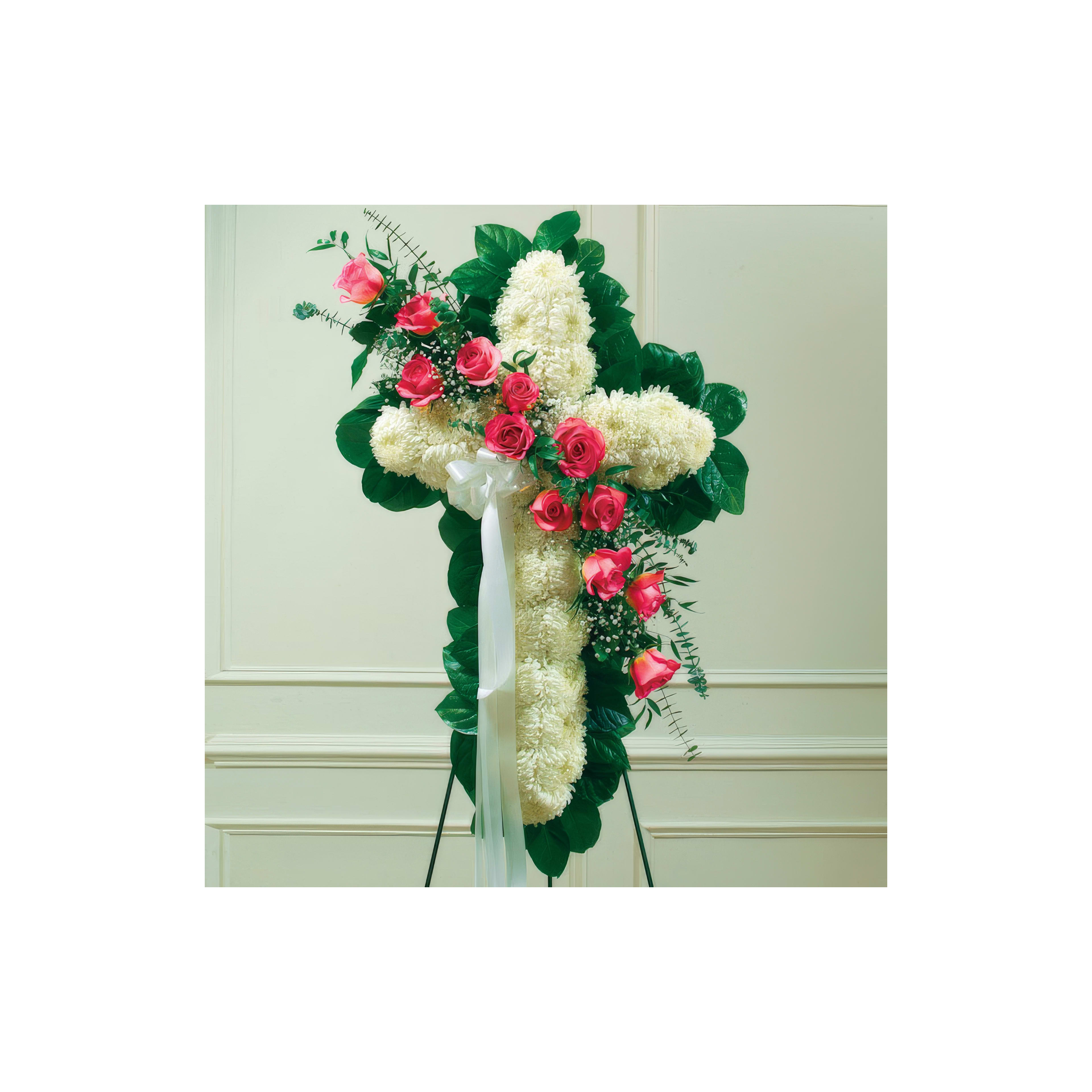 A cross-shaped floral arrangement has white chrysanthemums, pink roses, and green leaves.