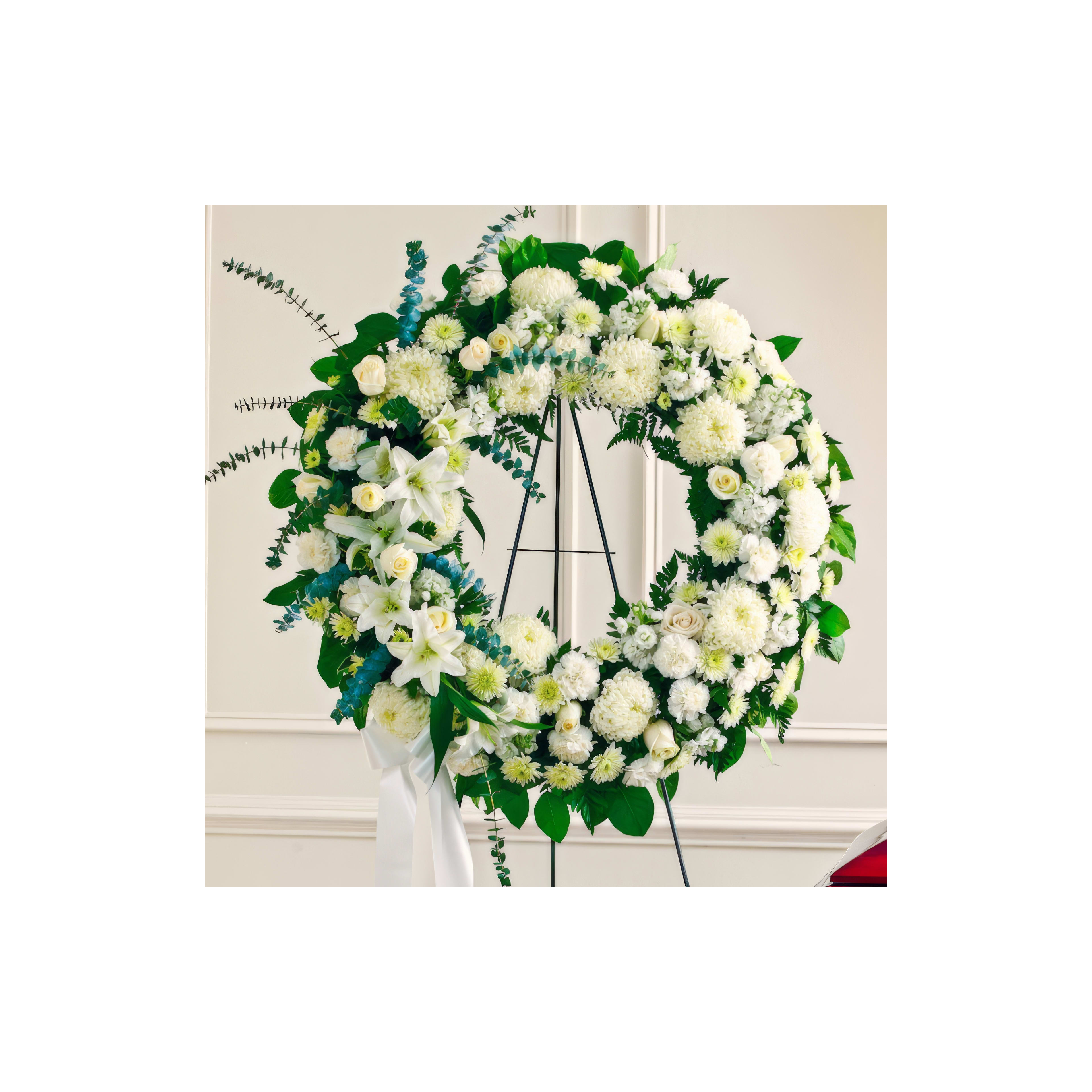 An elegant floral wreath of white flowers perfect for a memorial setting.