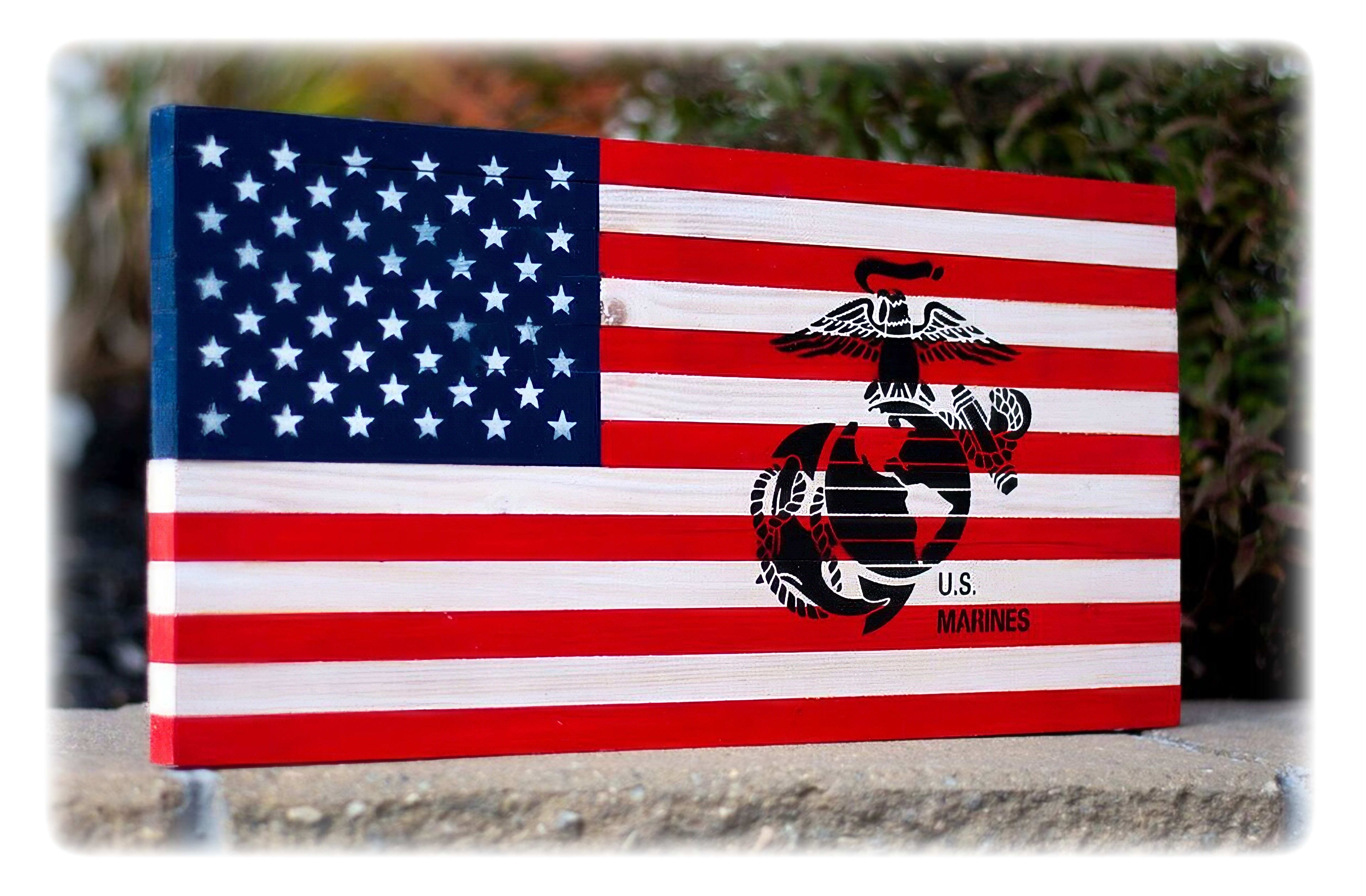 A wooden sign shows the American flag alongside the Marine Corps emblem against a natural backdrop.