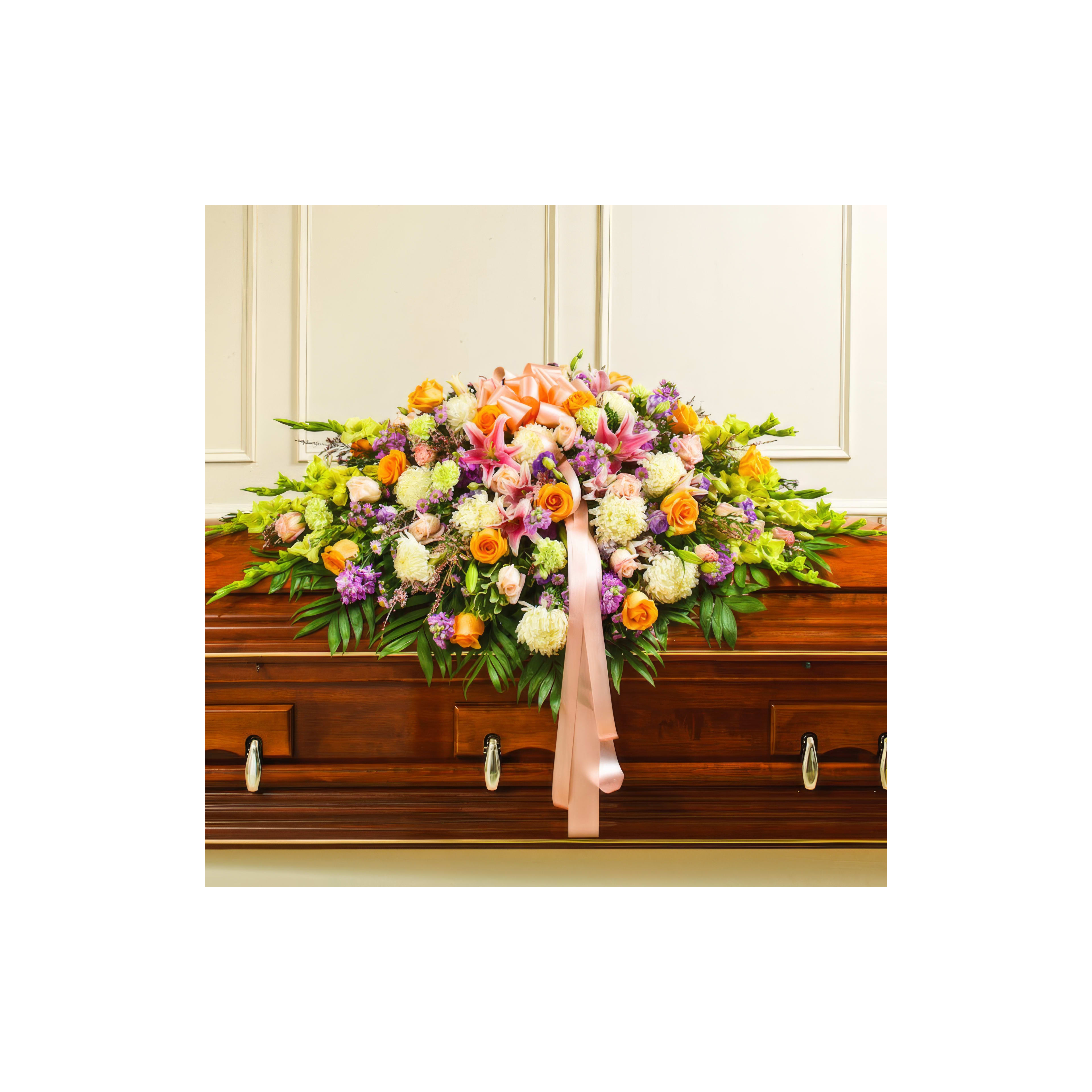 A vibrant display of flowers rests on a wooden casket at a solemn memorial setting.