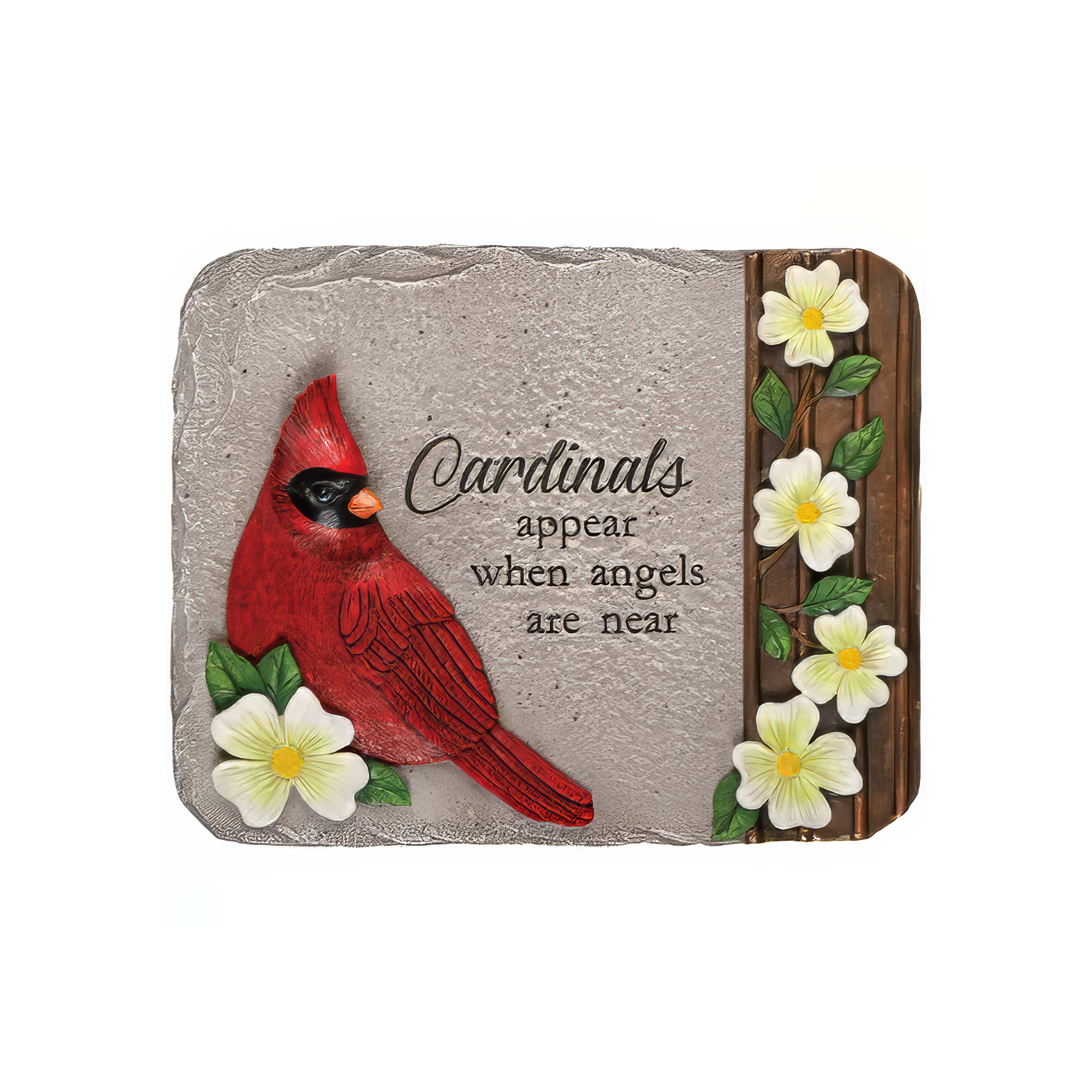 A vivid cardinal sculpture with a meaningful quote surrounded by white flowers in a garden.