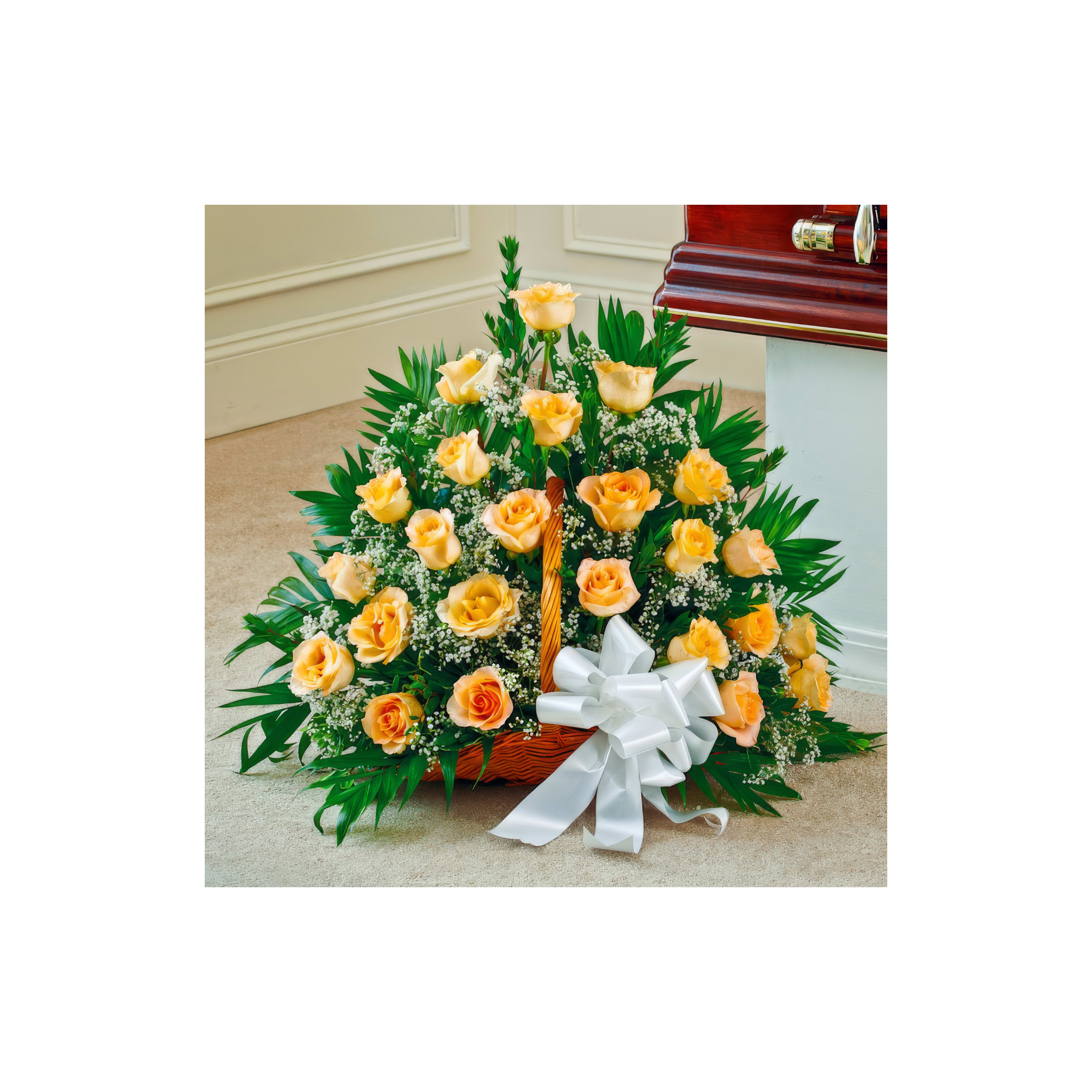 A bright basket of yellow roses and greenery, tied with a white bow, beside a casket.