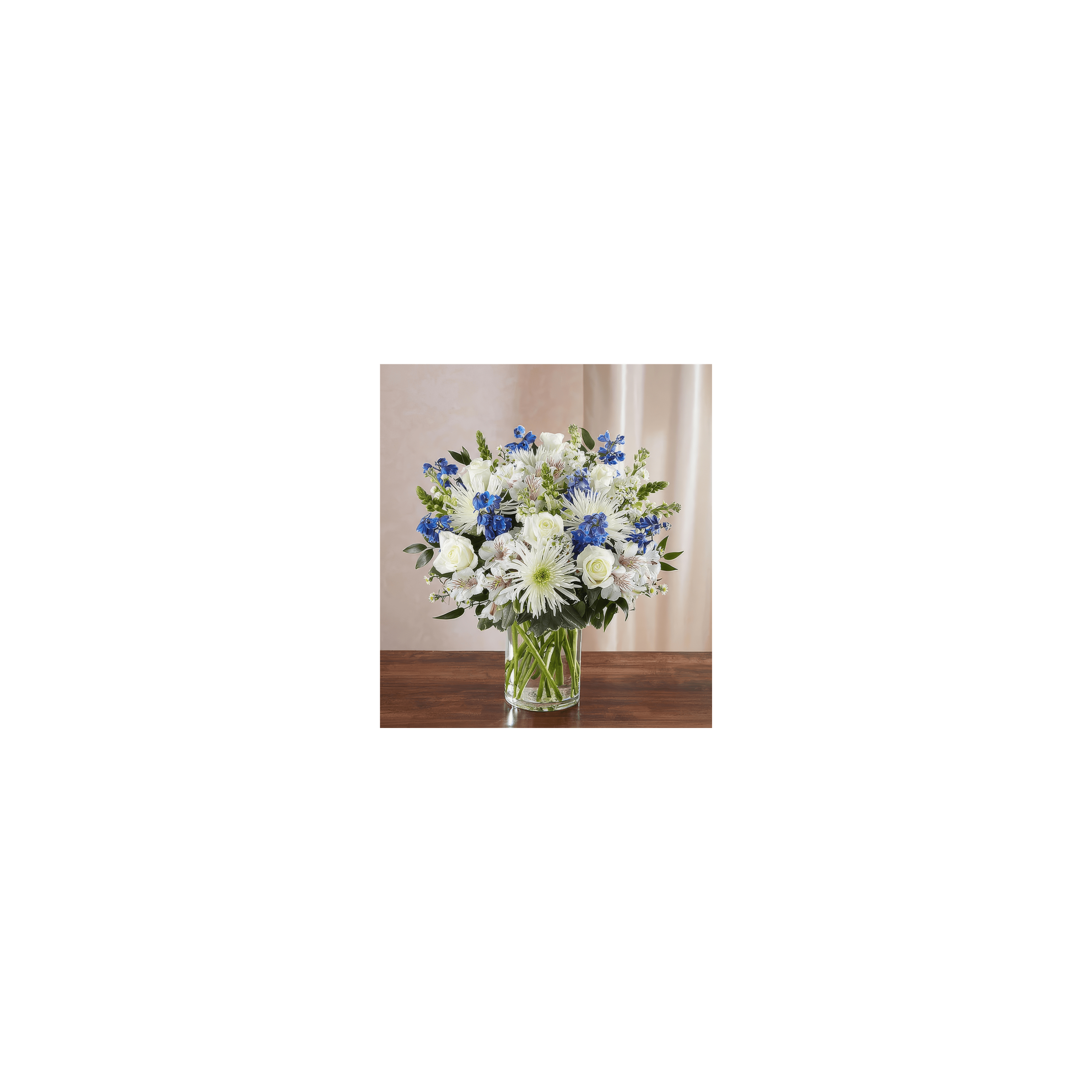 An elegant arrangement of white roses, blue blooms, and green leaves in a glass vase.