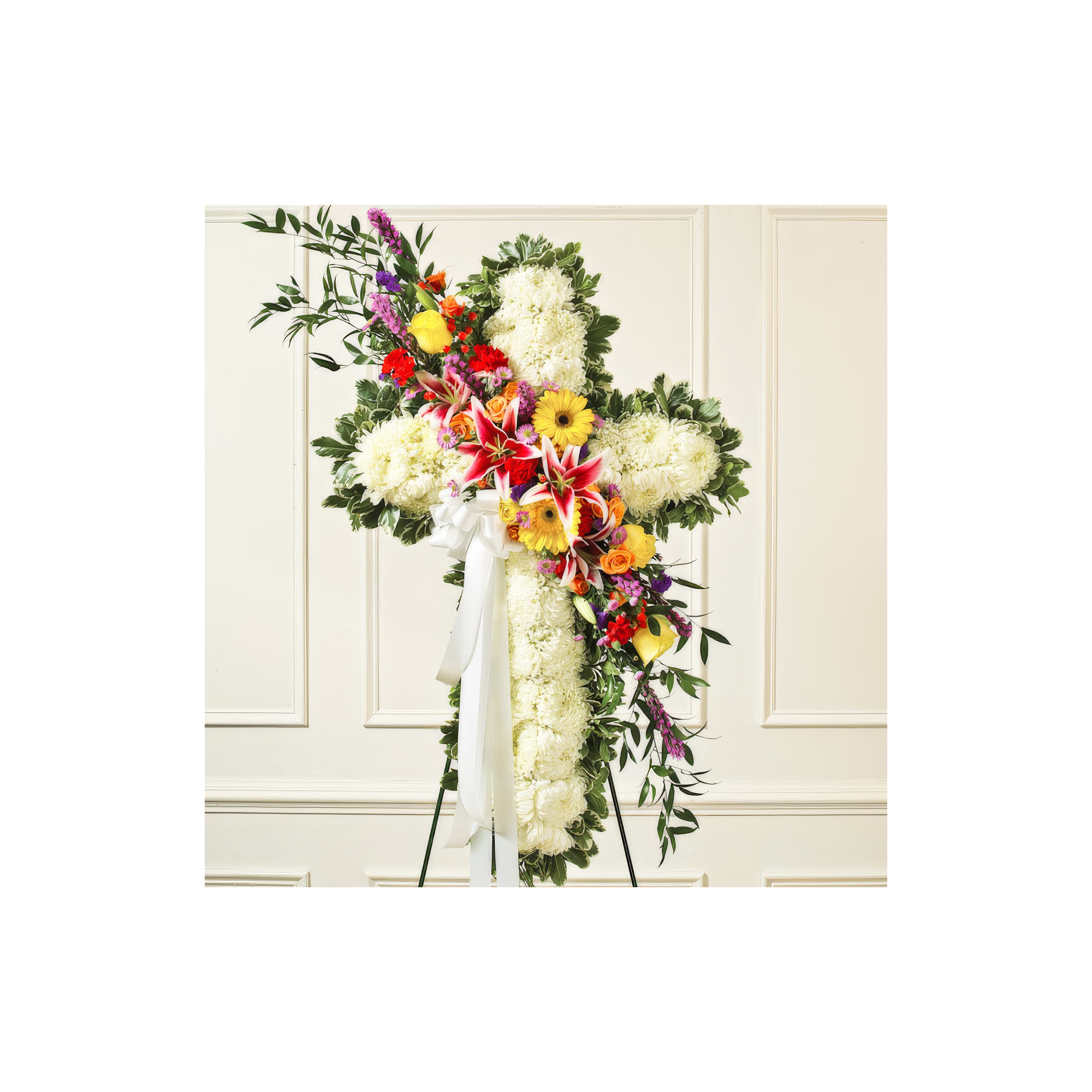 A cross crafted from white flowers with vibrant blooms showcases love and remembrance.