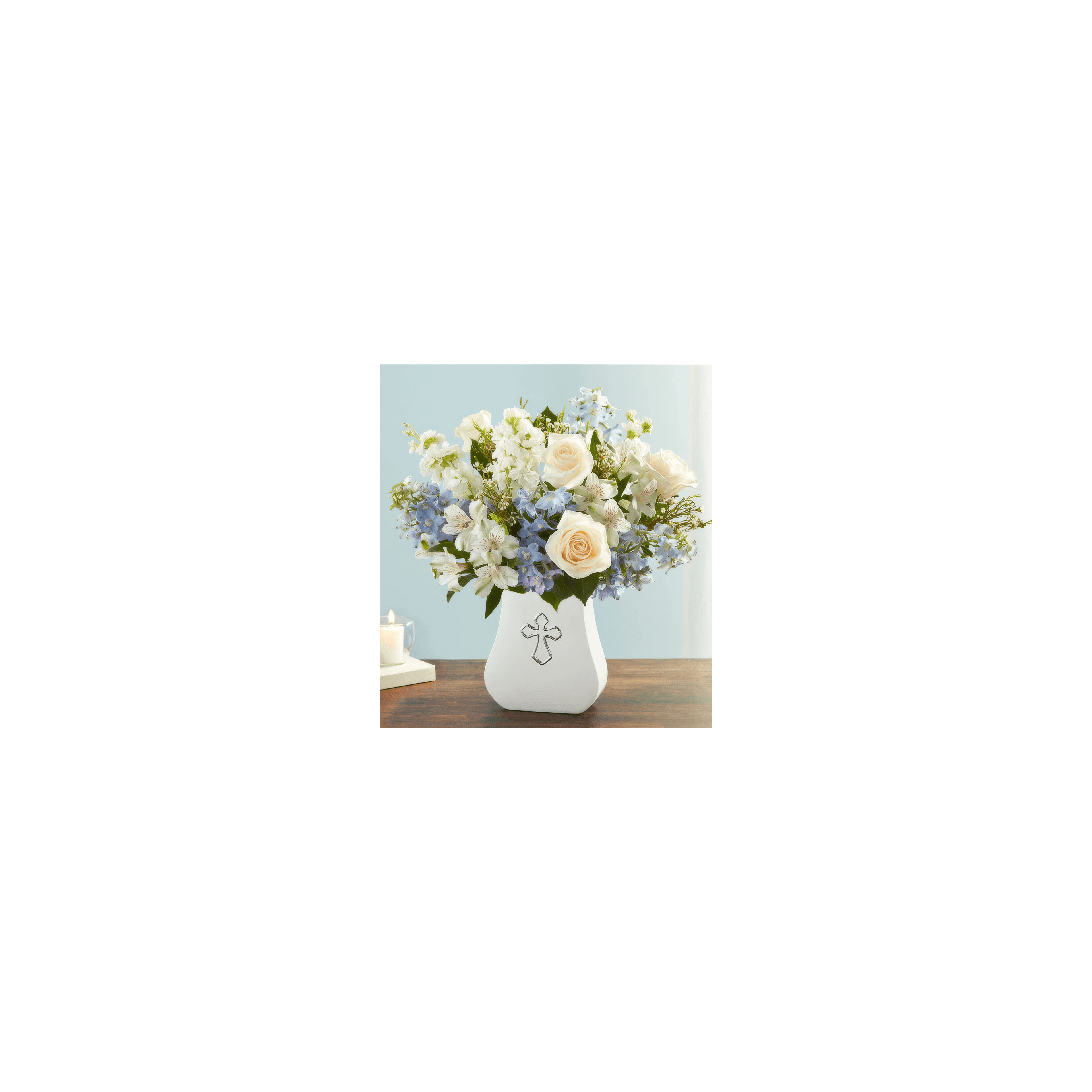 Delicate flowers of various colors displayed in a white cross vase on a wooden surface.