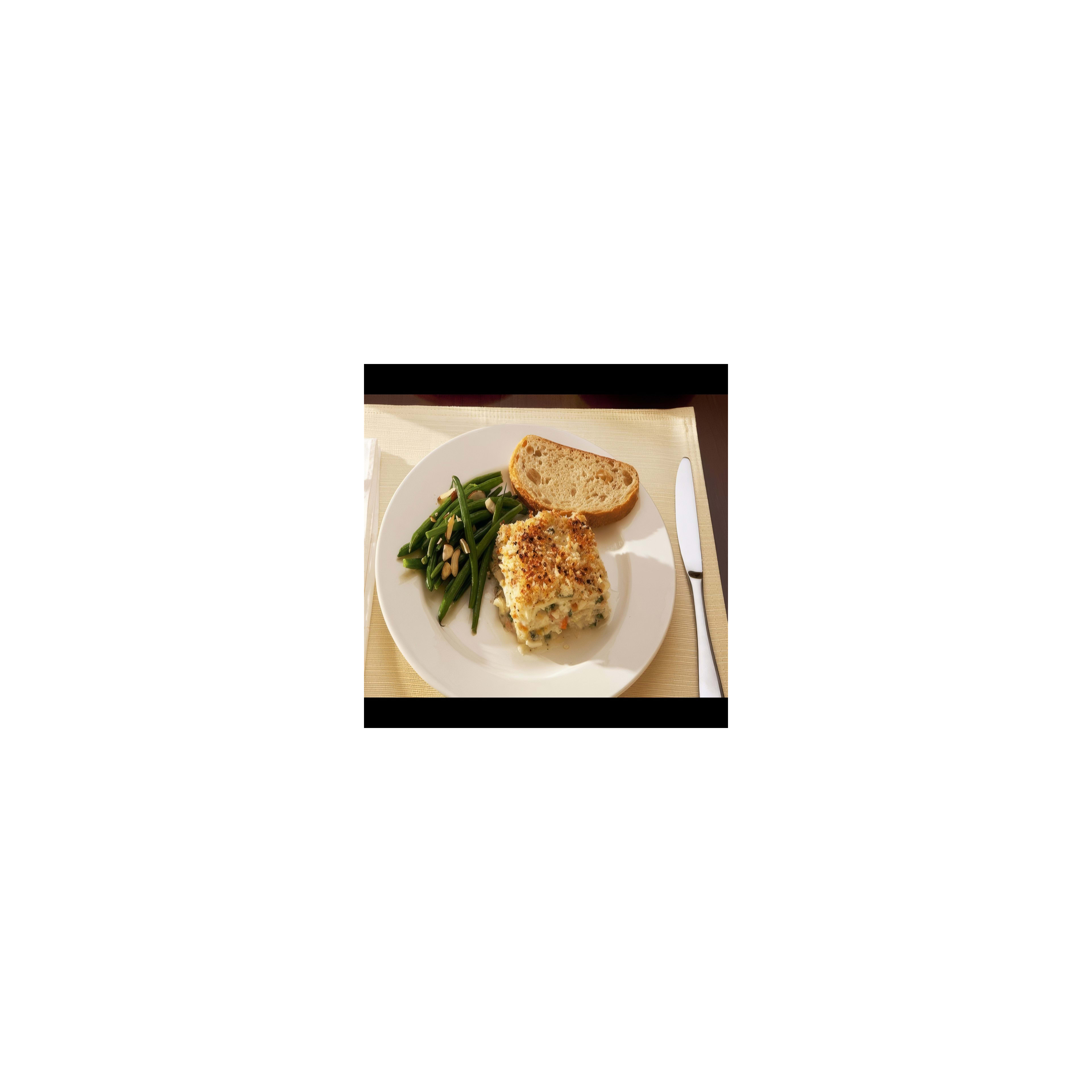 A warm casserole dish accompanied by green beans and a slice of rustic bread is served.