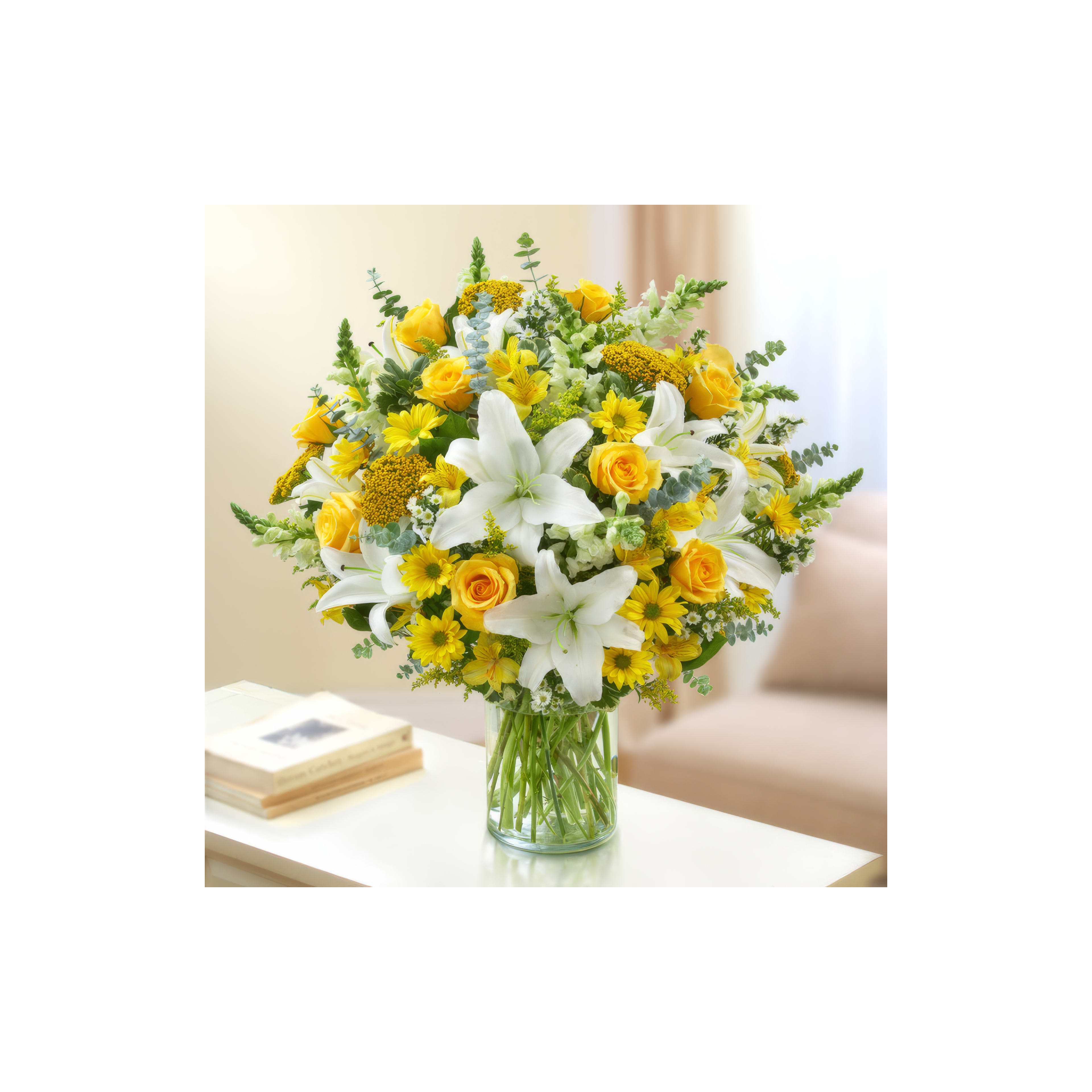 Bright bouquet of yellow roses, white lilies, and sunflowers on a table in a softly lit room.