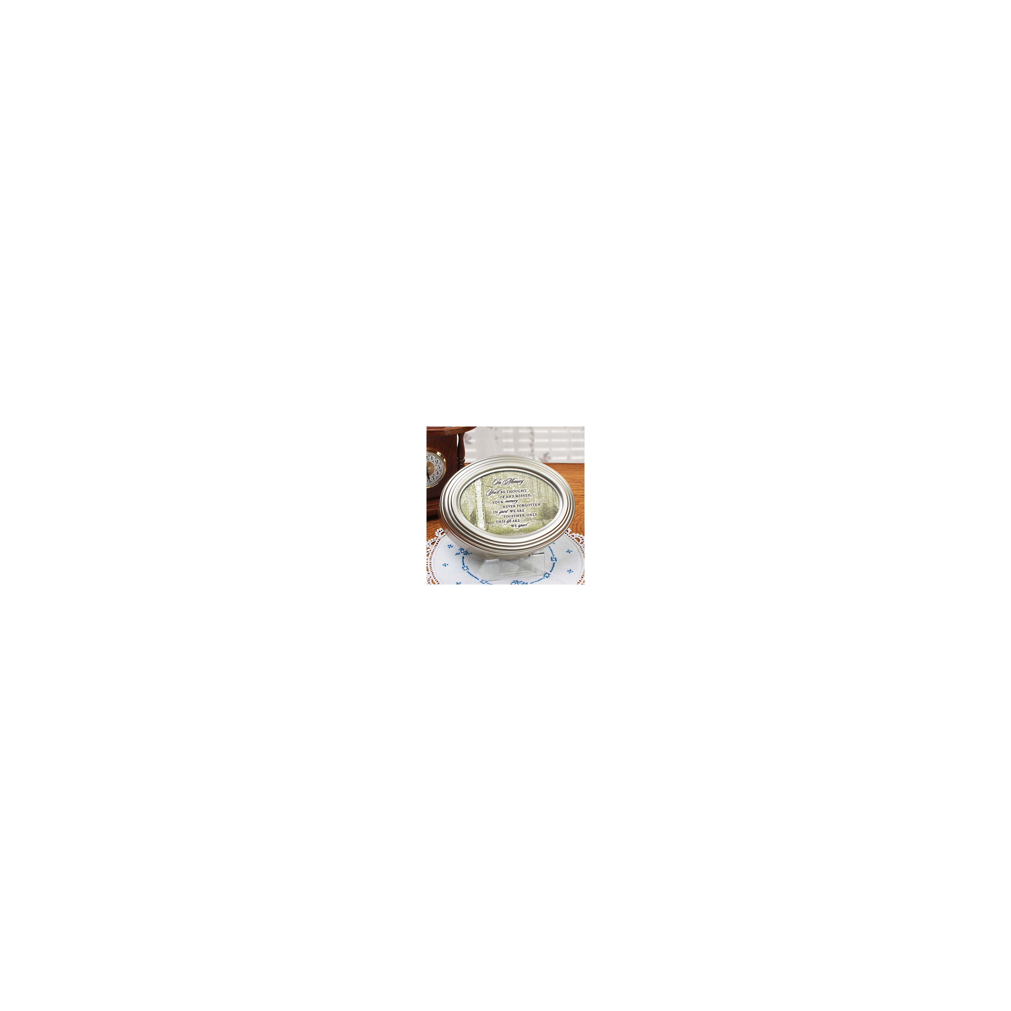 A memory frame holds a sentimental message and is surrounded by a clock and lace doily at a table.