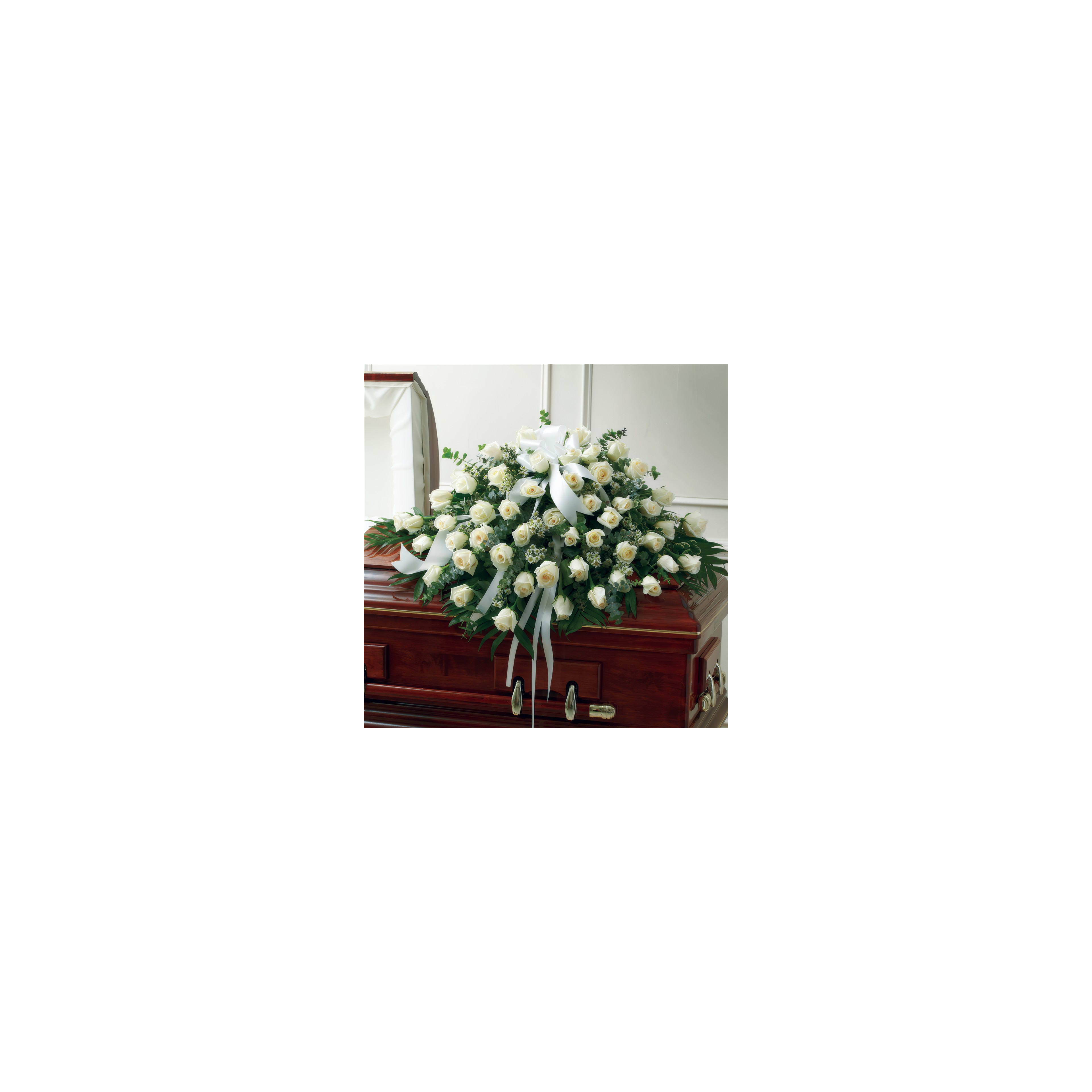 A beautiful display of white roses rests on a wooden casket in a quiet environment.