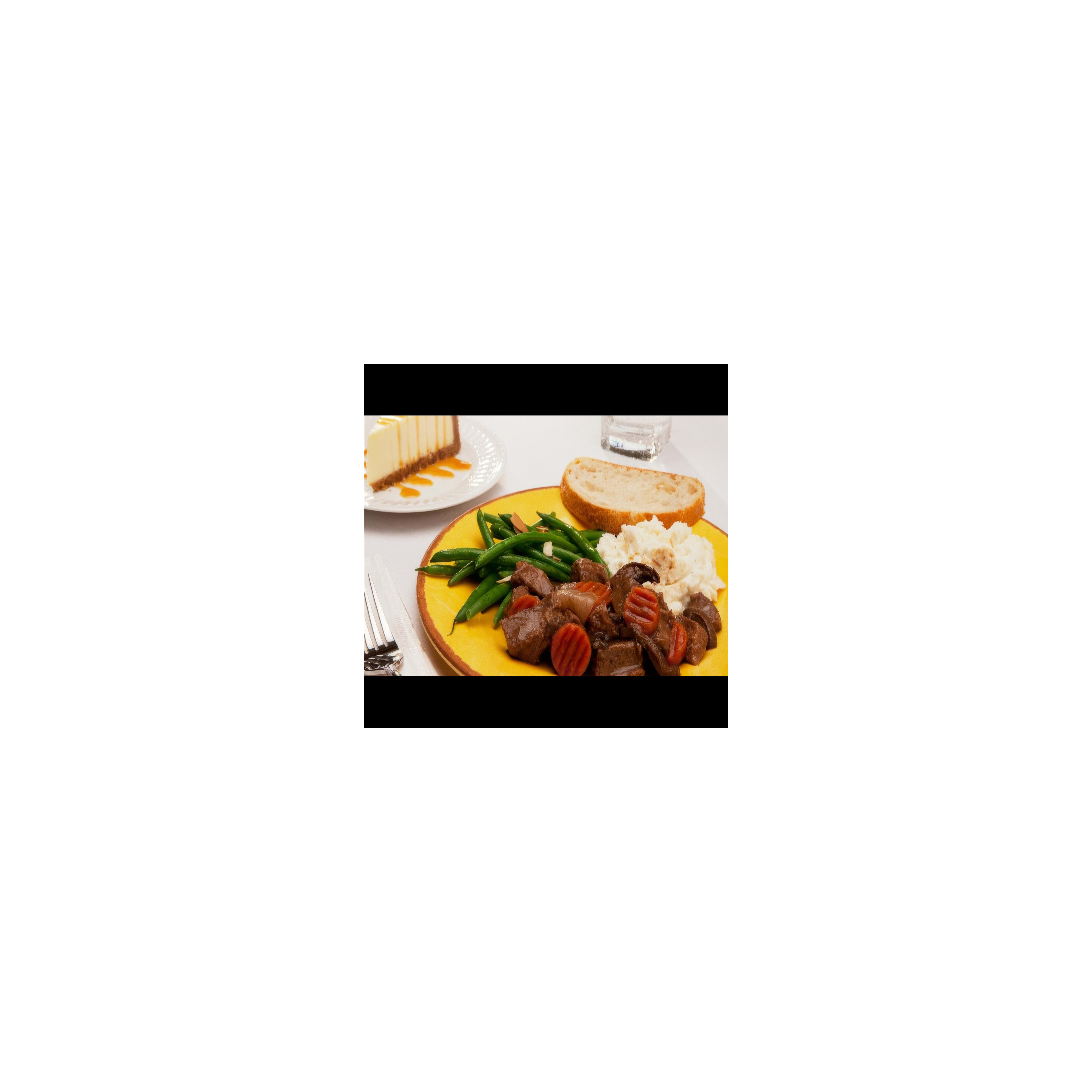 A hearty dinner plate with beef stew, green beans, mashed potatoes, and a side of cheesecake.