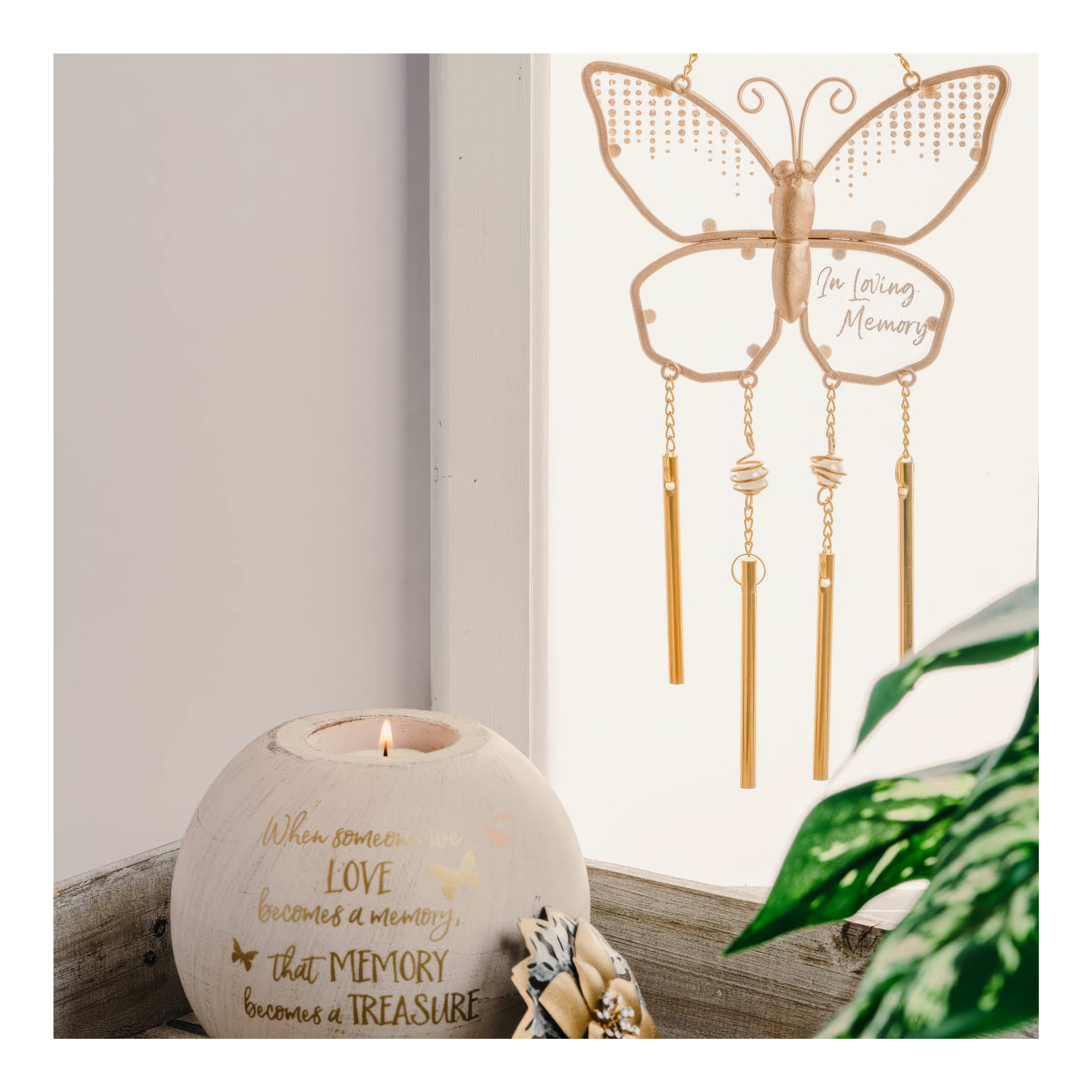 A lovely butterfly decor piece hangs beside a candle, creating a soothing atmosphere with greenery.
