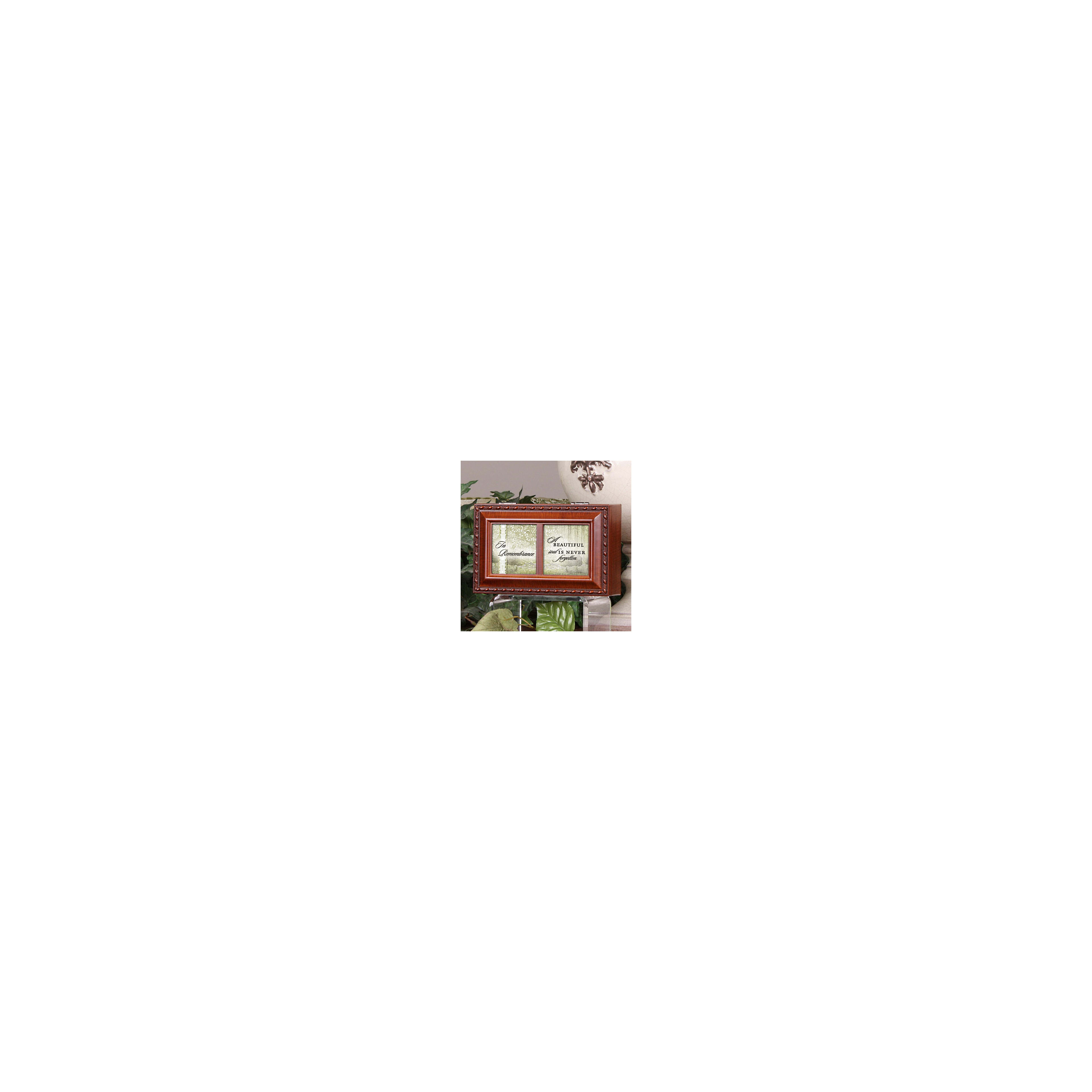 A wooden memorial box with a touching inscription sits elegantly amid lush green plants.