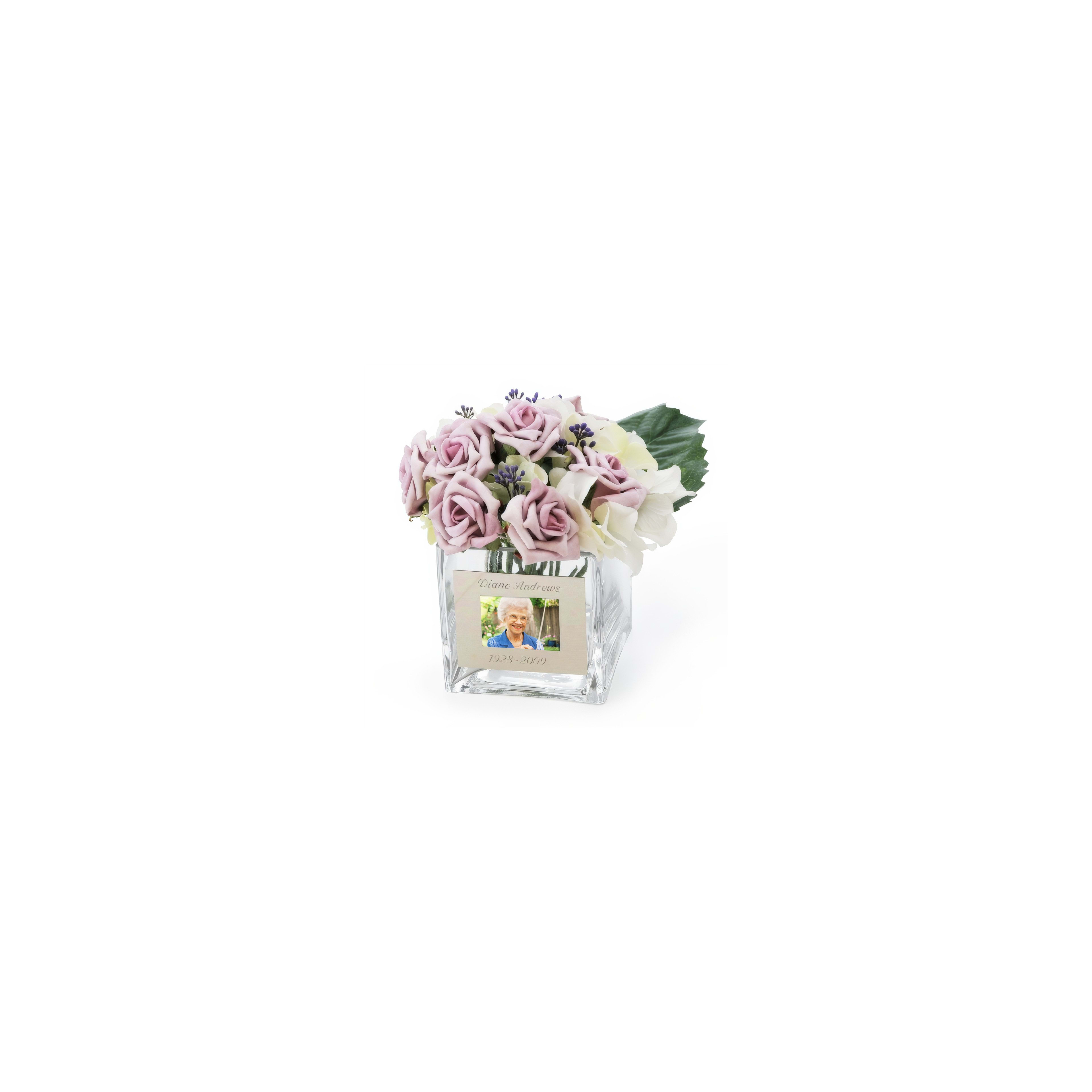 A floral arrangement features lavender roses and white blooms with a photo honoring a loved one.