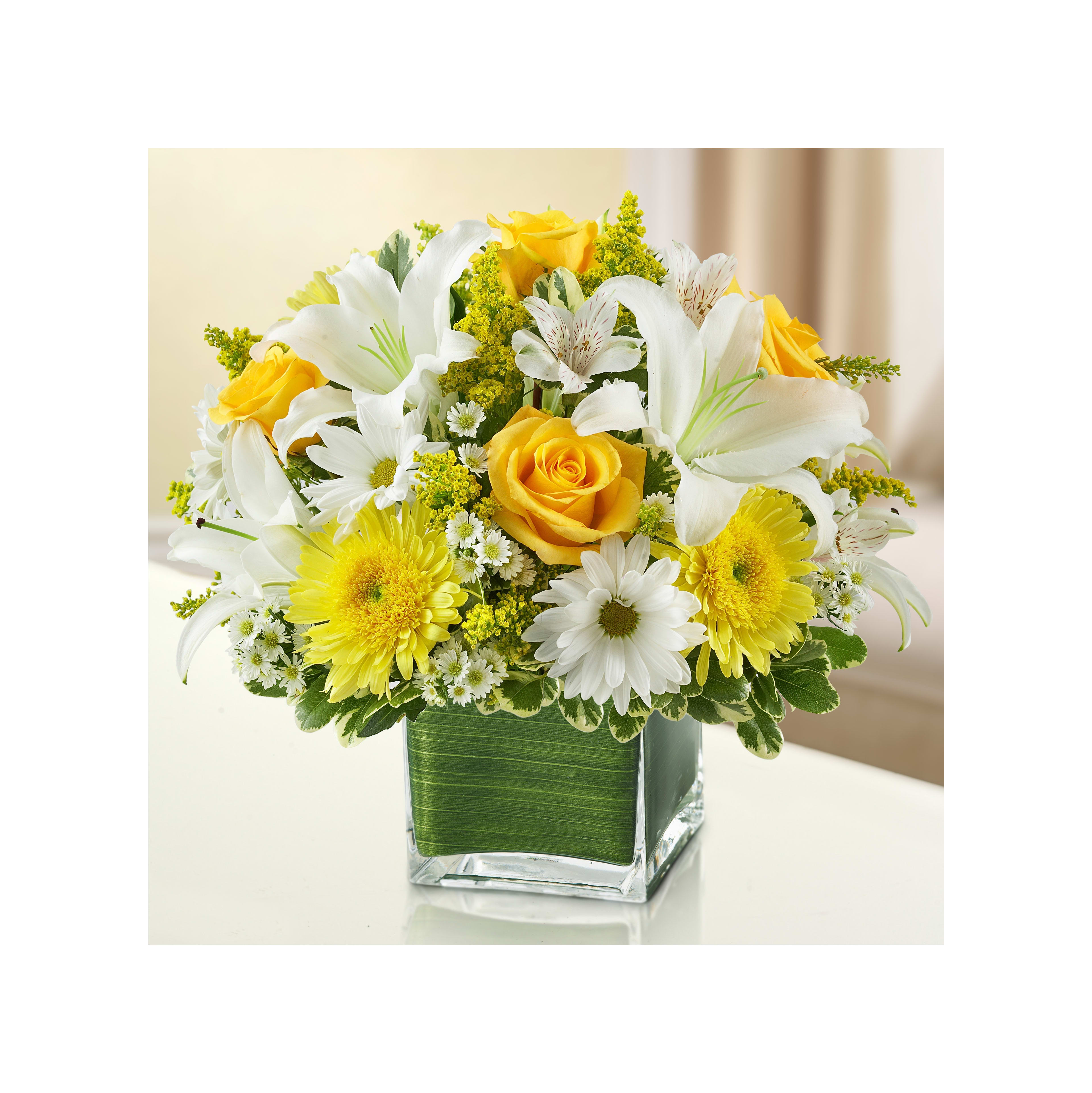Colorful flowers in a clear vase brighten up a table in a softly lit room.