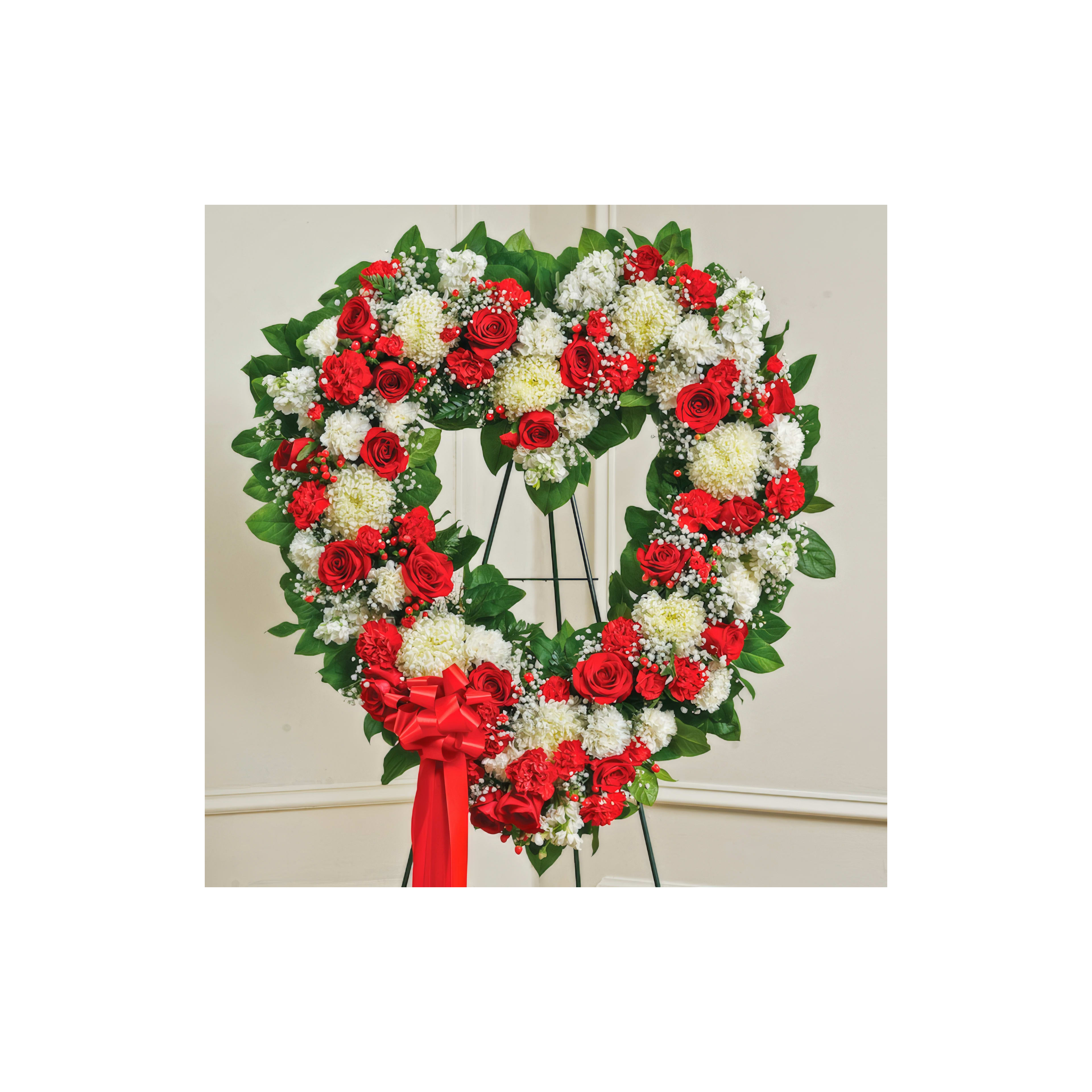 Heart-shaped floral tribute features red roses and white chrysanthemums on a stand.