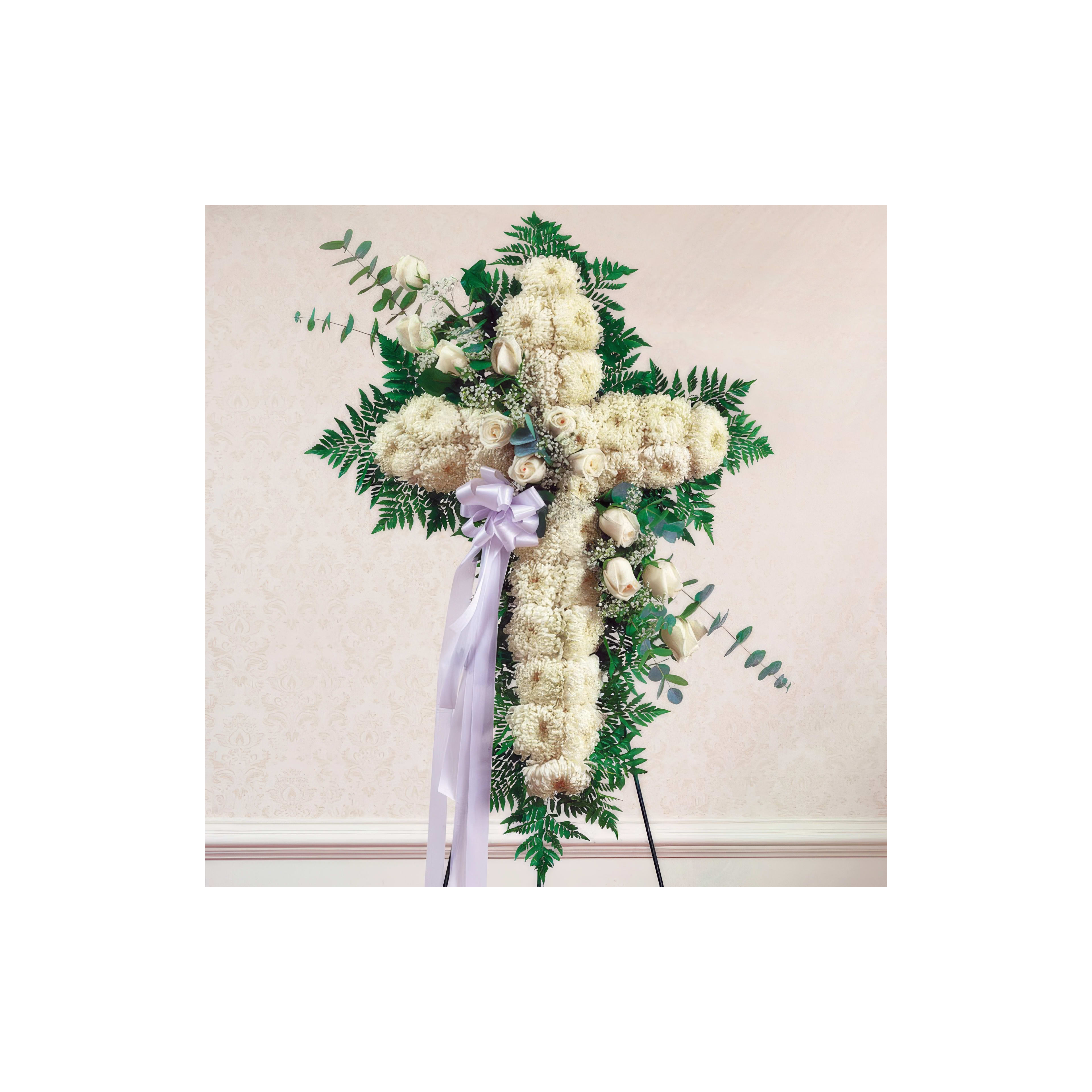 A stunning floral cross adorned with white roses and greenery is on display.