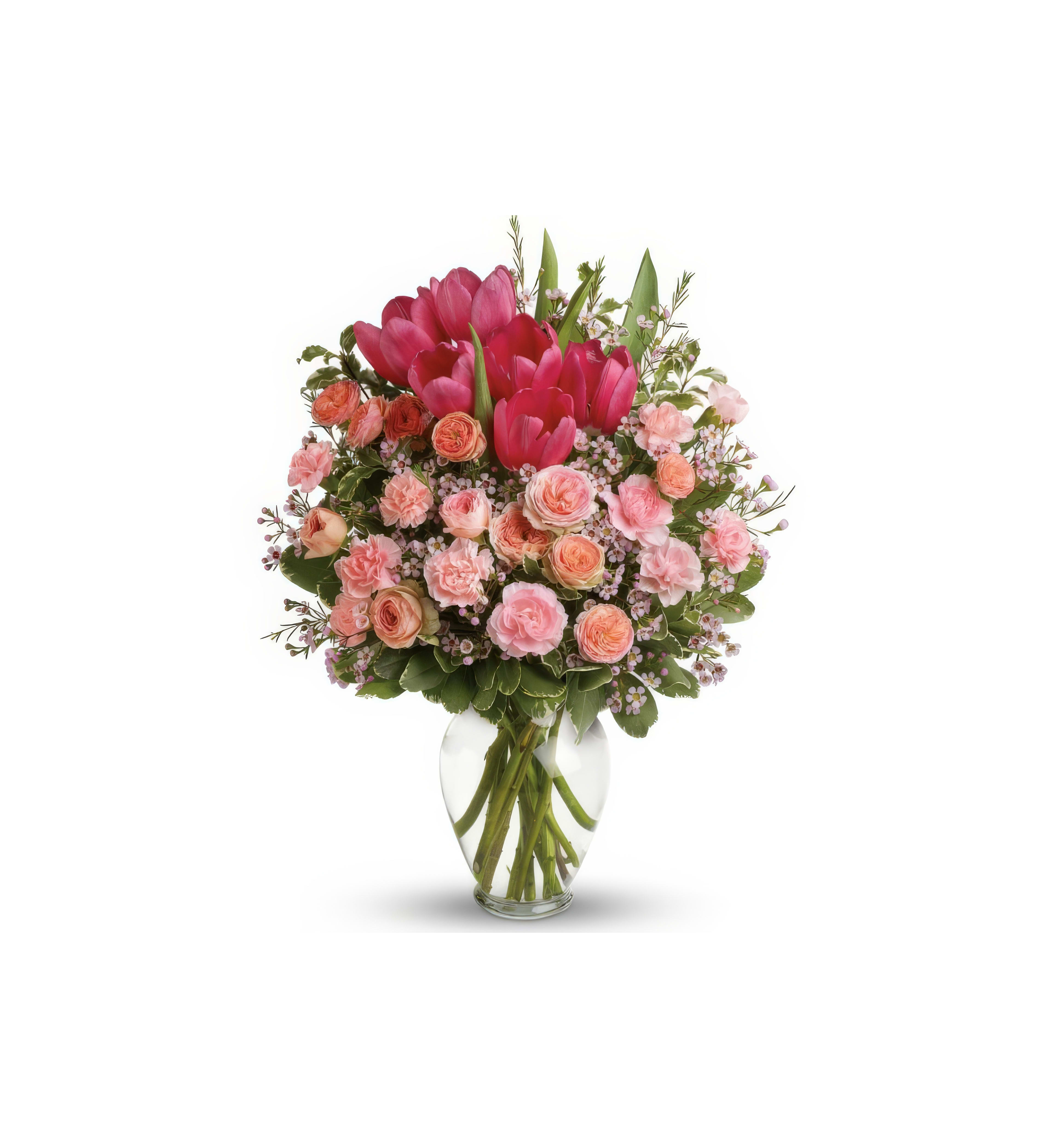 A vibrant bouquet showcases pink tulips and roses alongside greenery in a glass vase.