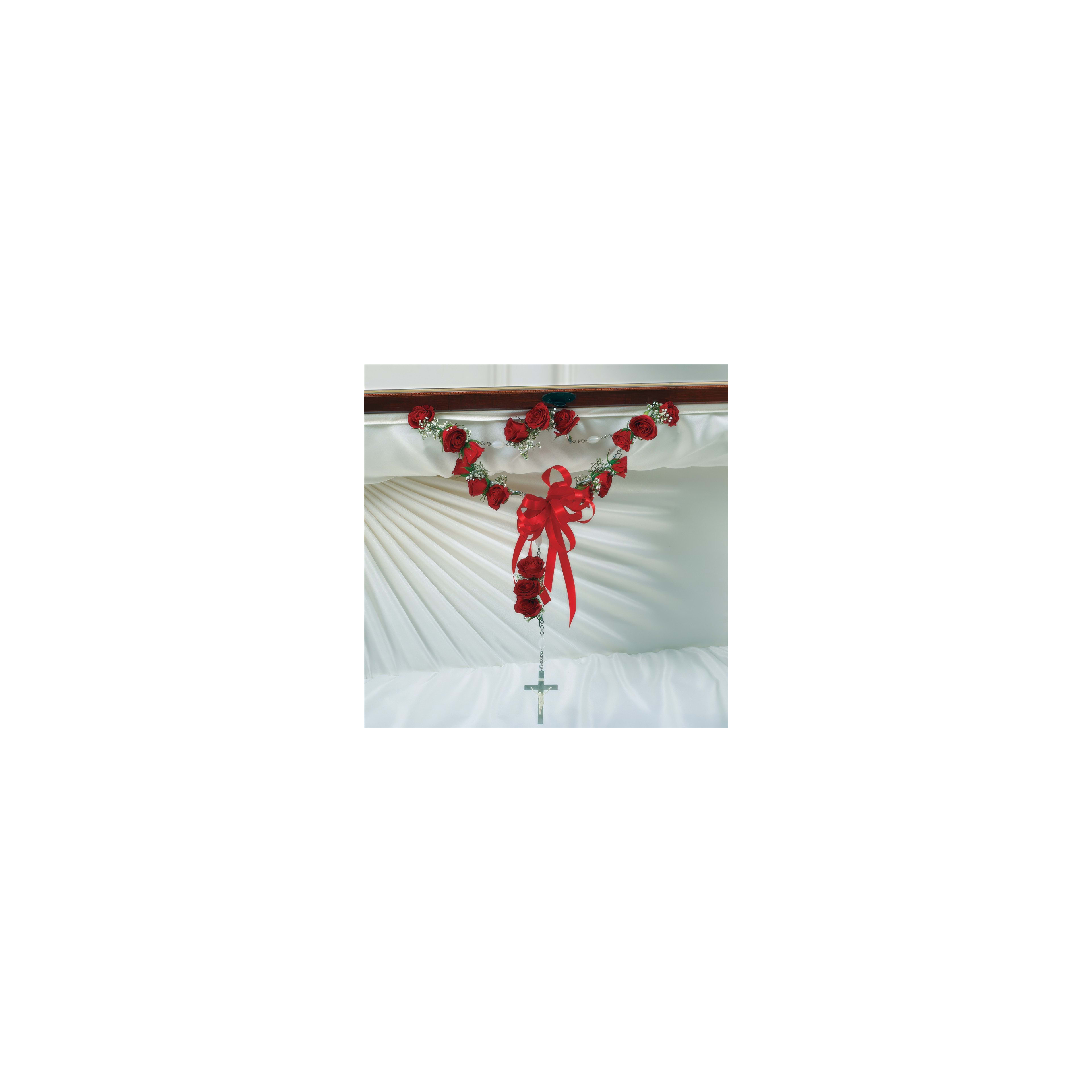 Red roses and greenery are arranged beautifully with a cross for honoring a loved one.