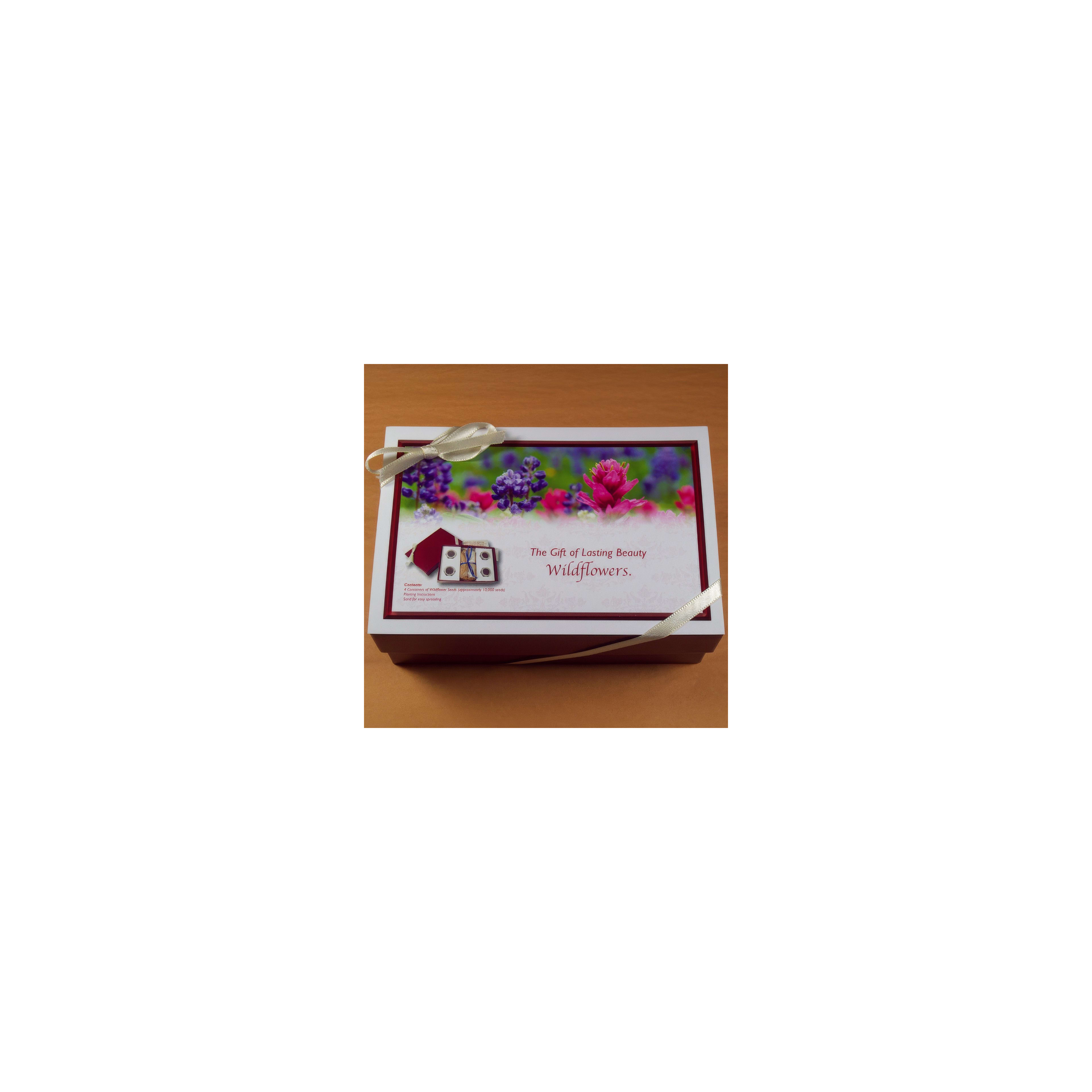A decorative gift box features vibrant wildflowers and is tied with a ribbon on a wooden table.