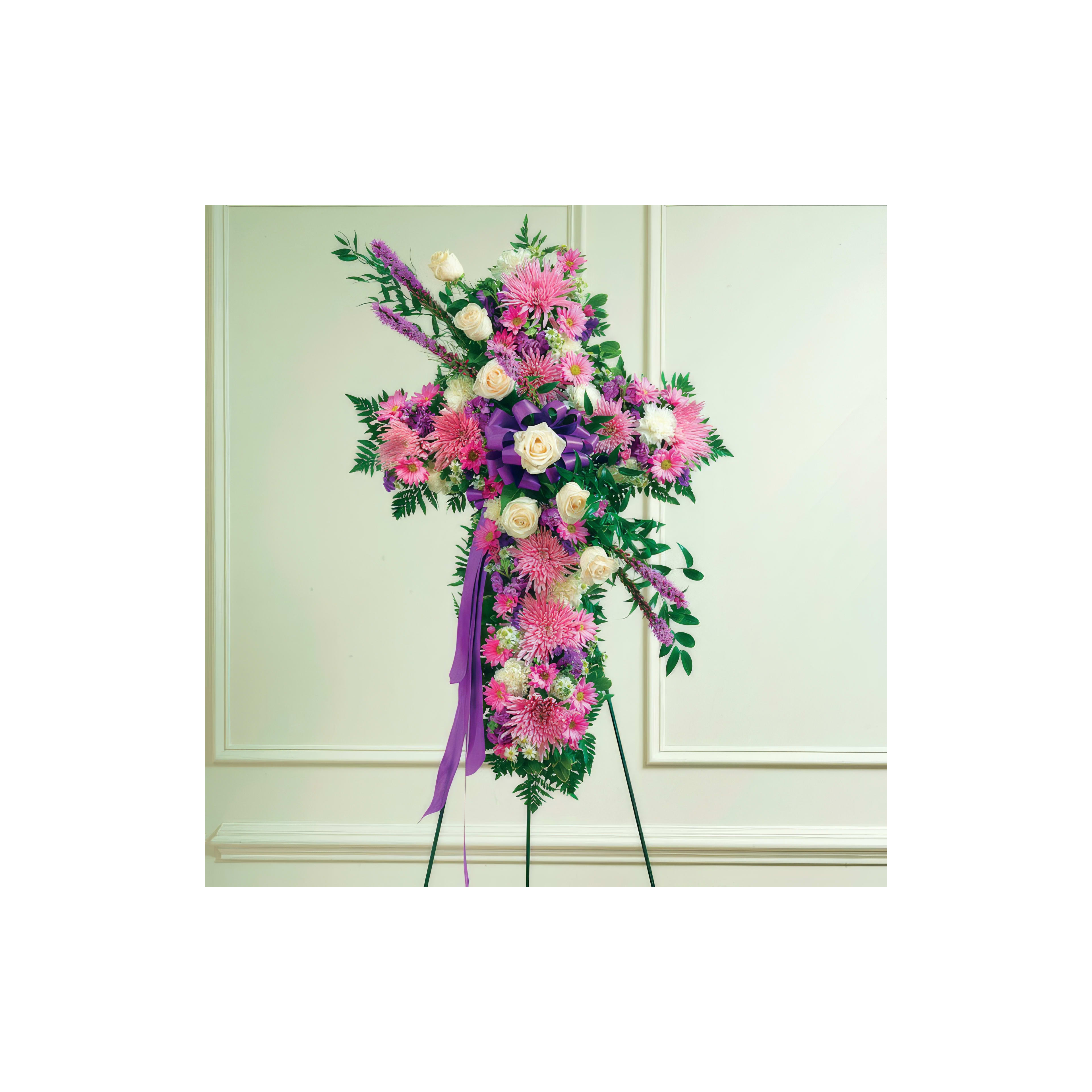 A colorful floral tribute features pink and white blossoms arranged in the shape of a cross indoors.