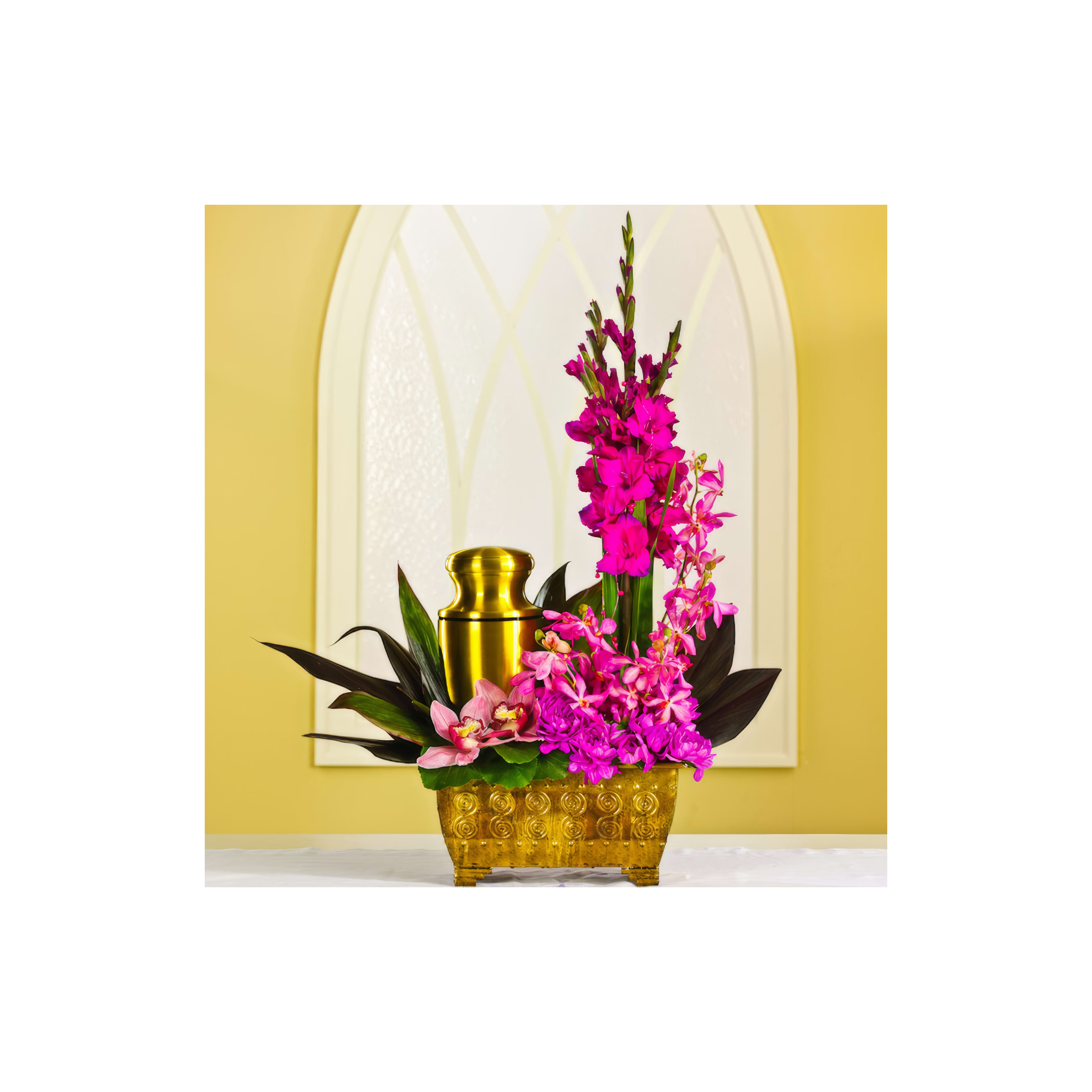 Bright pink flowers arranged with a golden vase create a stunning focal point in a warm setting.