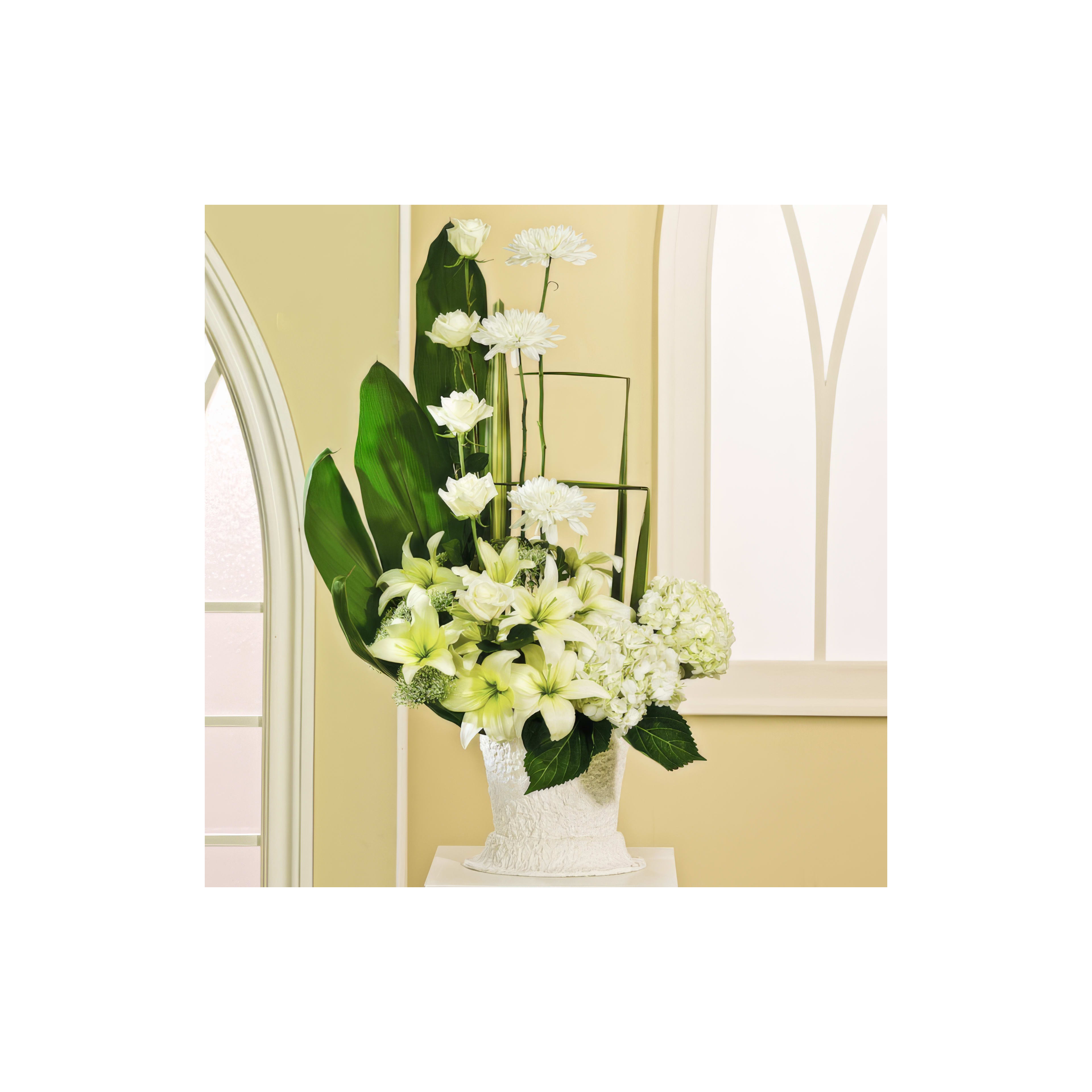 Fresh white flowers including lilies and hydrangeas create a stunning arrangement in a sunny space.