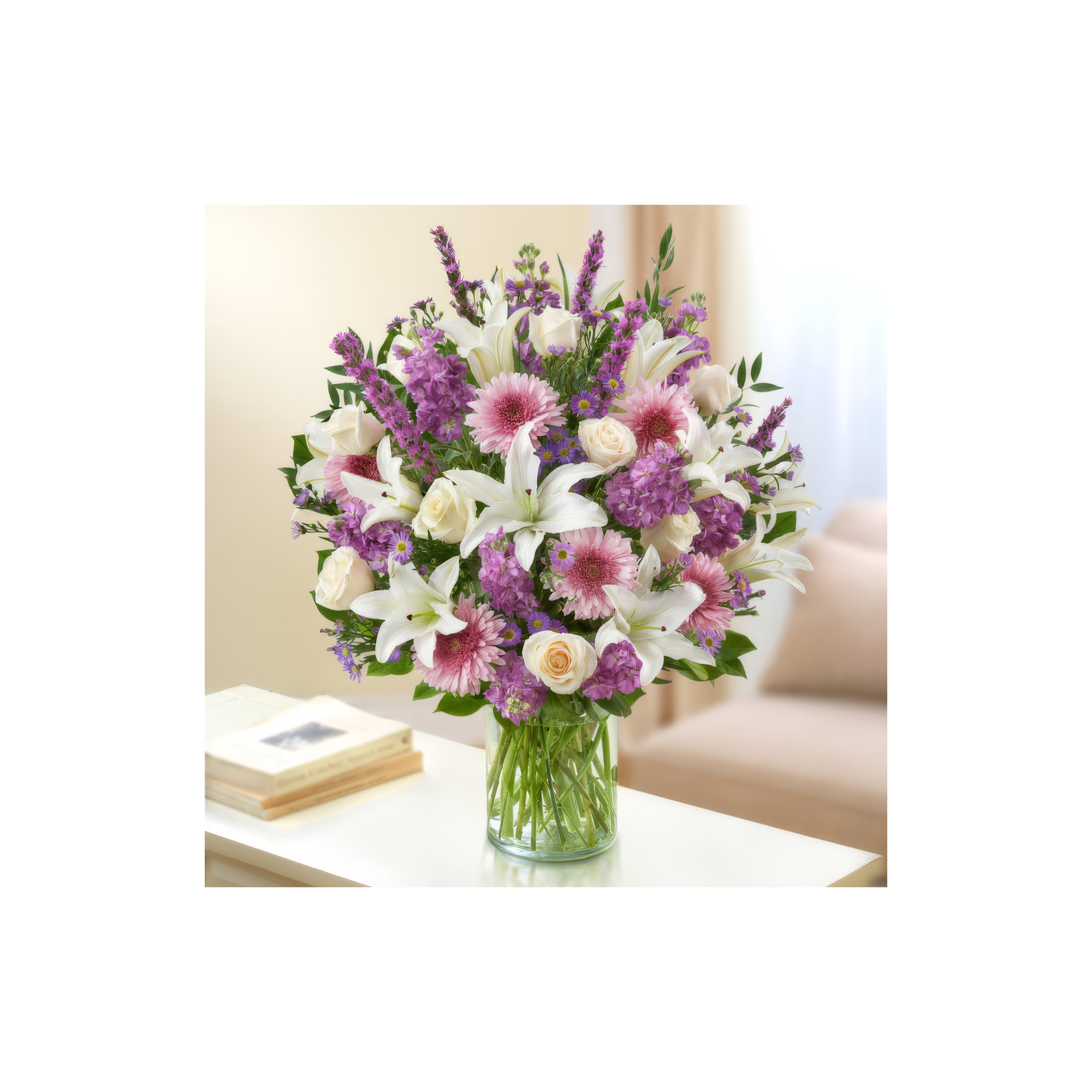A vibrant bouquet featuring lilies, roses, and daisies is displayed in a clear vase on a table.