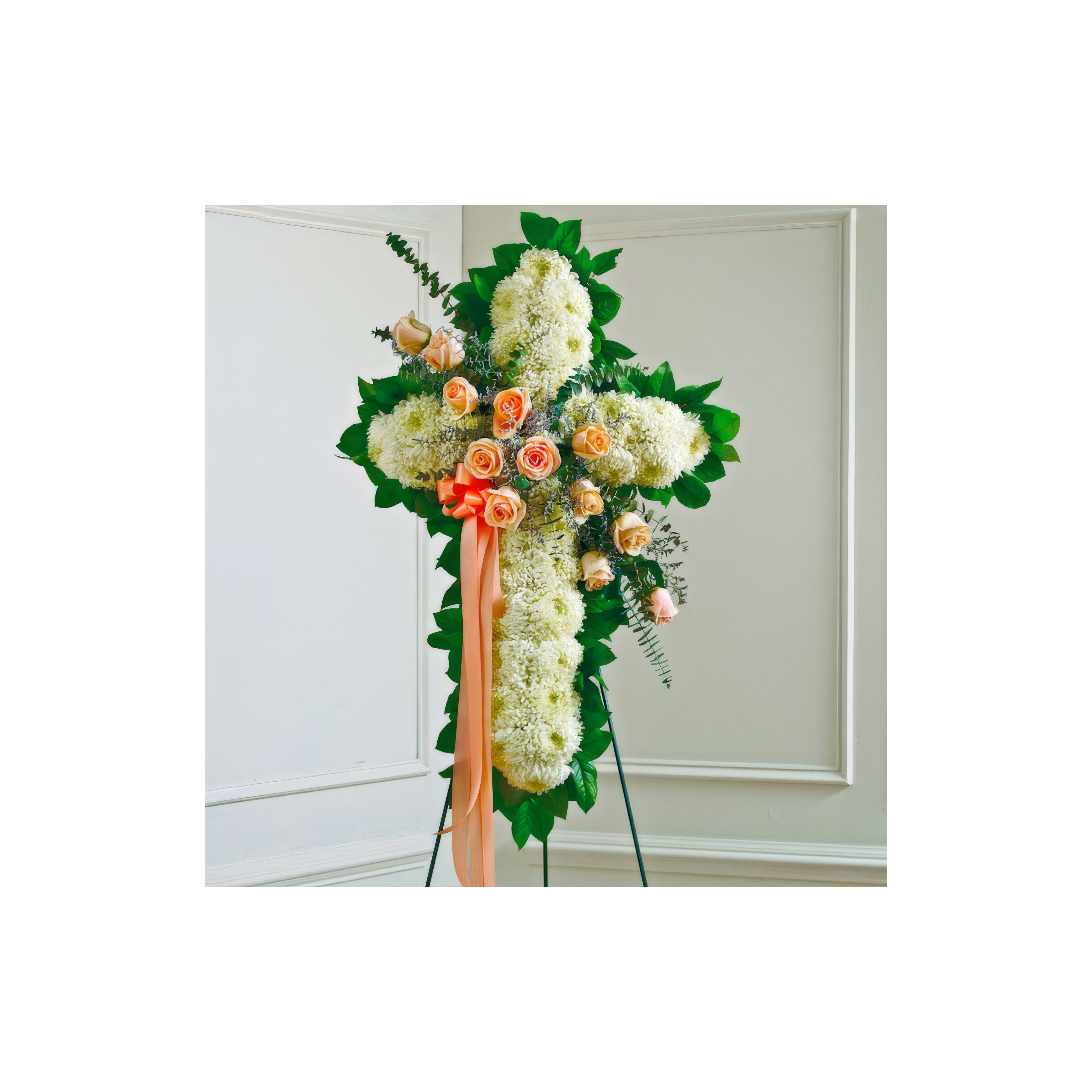 A beautifully crafted floral cross features roses and lush greenery, serving as a tribute piece.