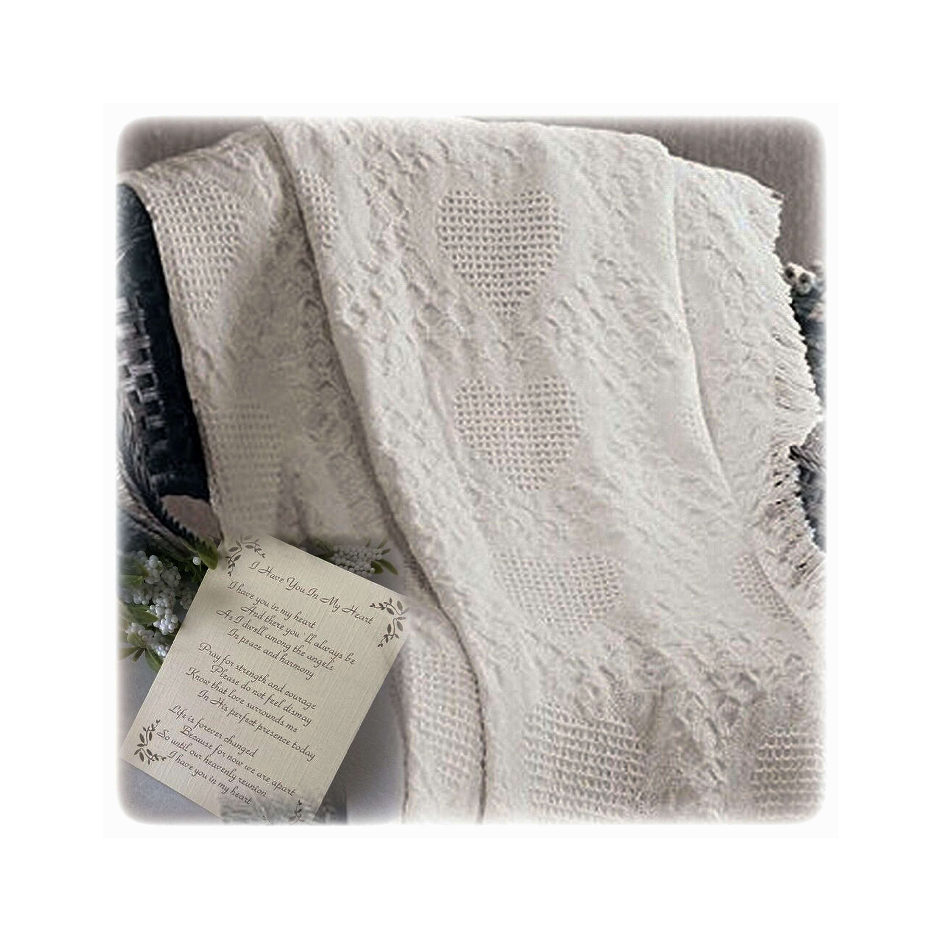 A cozy white blanket with heart designs rests beside a touching note on a textured surface.