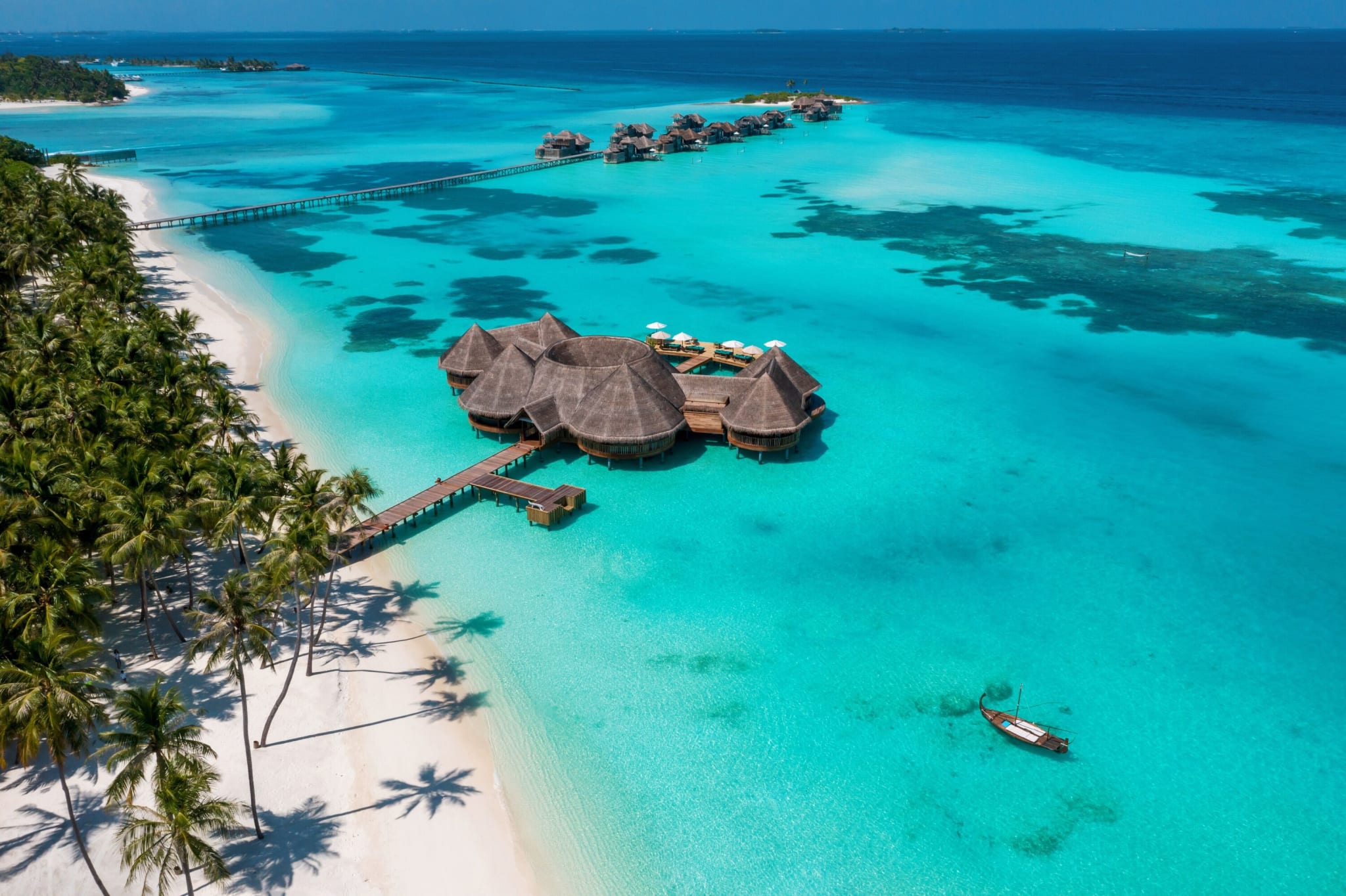 Overvannsvillaer på Gili Lankanfushi sett fra lufta, med strand og turkis lagune.