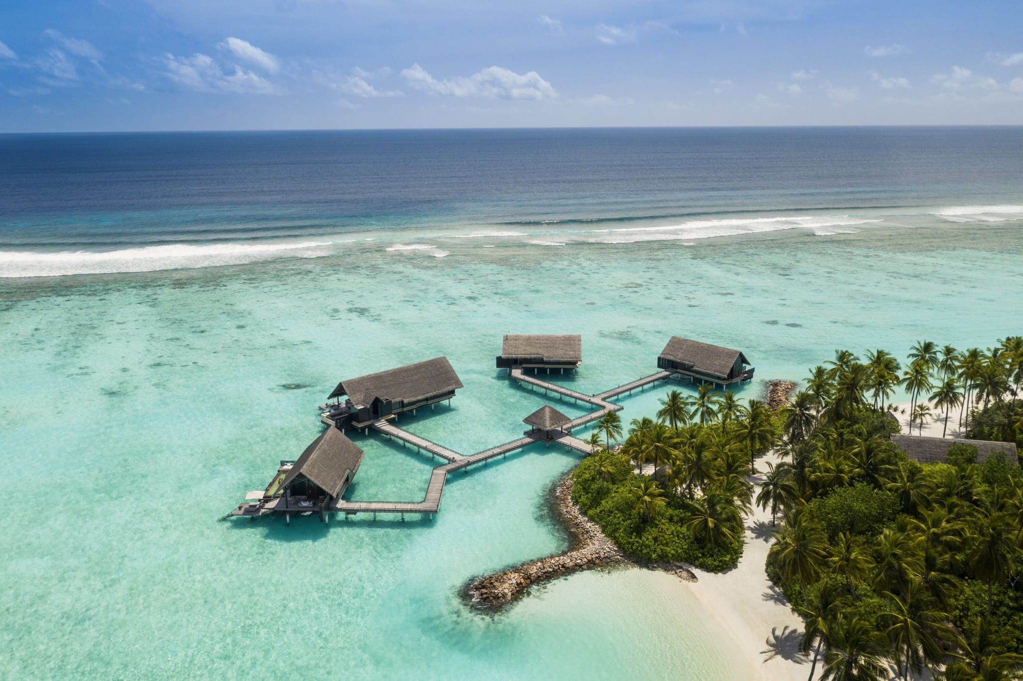 Overvannsvillaer ved One&Only Reethi Rah sett fra lufta, forbundet med en brygge.