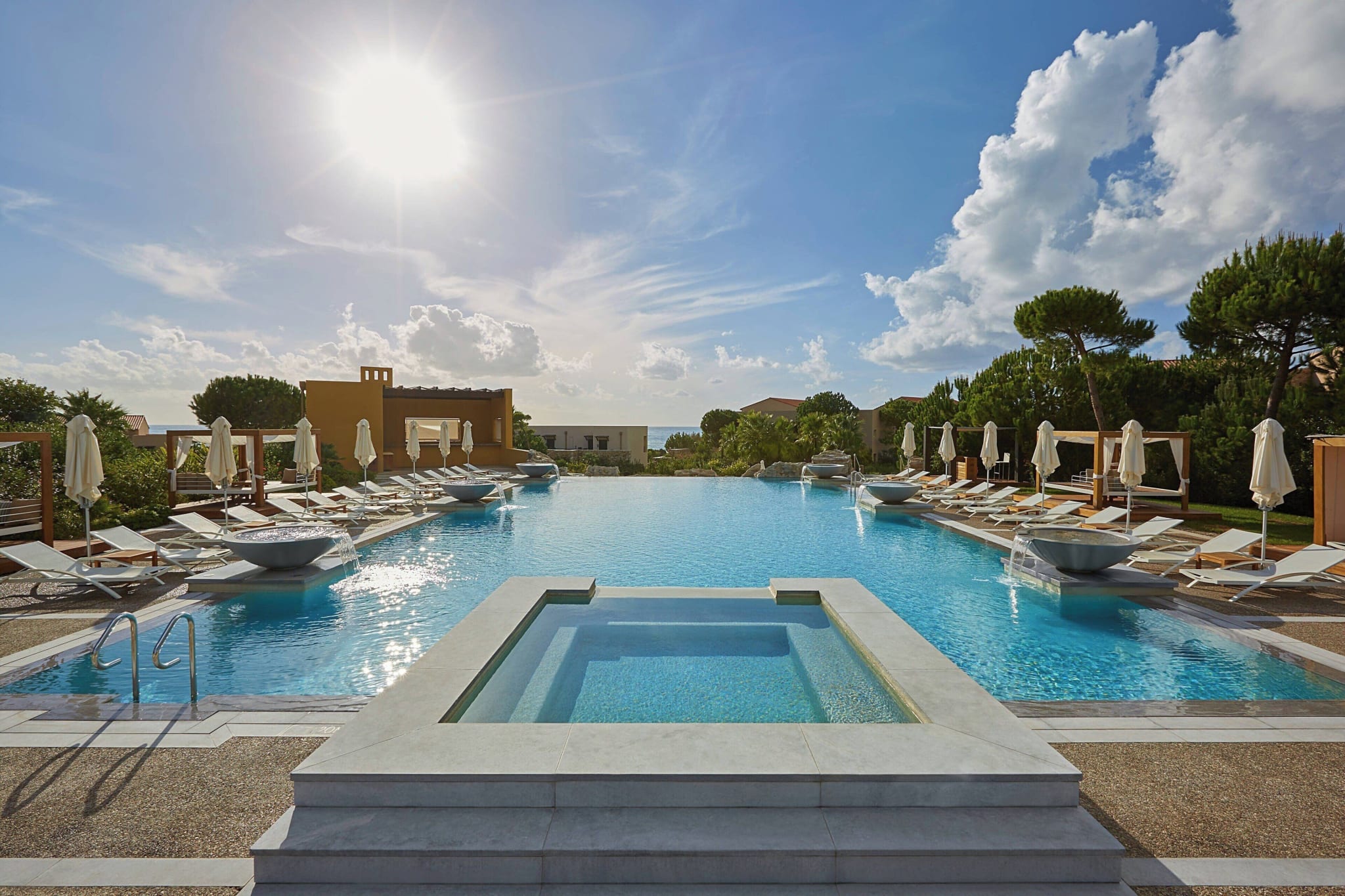 Bassenget ved The Westin Resort Costa Navarino med solsenger og Det joniske hav bak